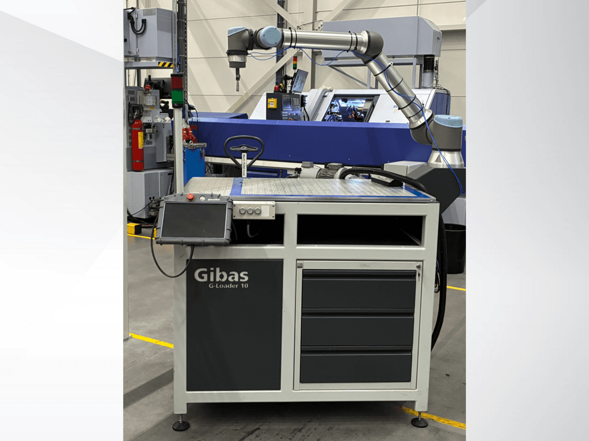 Gibas G-Loader 10 robottikäsivarren kanssa, etukuva; siinä on kosketusnäytön ohjaus ja laatikosto teollisuusympäristössä.