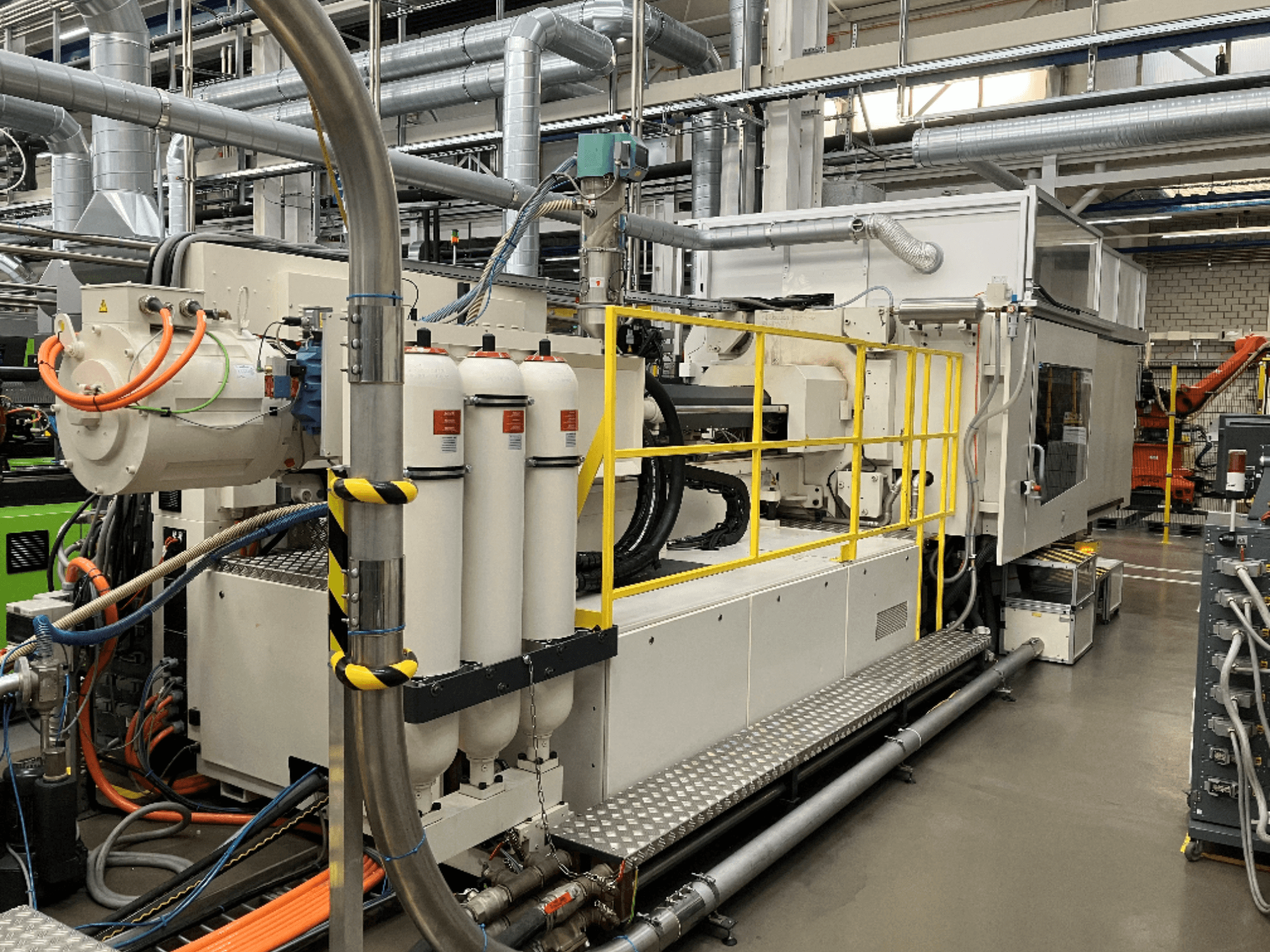 Teollisuuskone, jossa on valkoinen ja harmaa kotelo, useita letkuja ja suodatinsäiliöitä; sivukuva, jossa näkyy toiminta-asetukset.