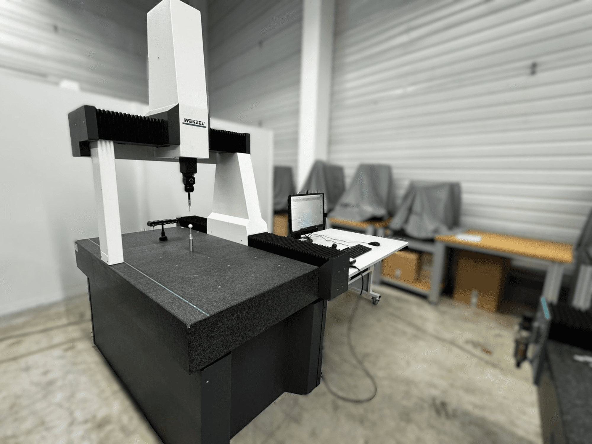 Wenzel LH 54 -koordinaattimittauskone sivukuvassa, jossa on anturi ja tietokoneliitäntä harmaalla alustalla.