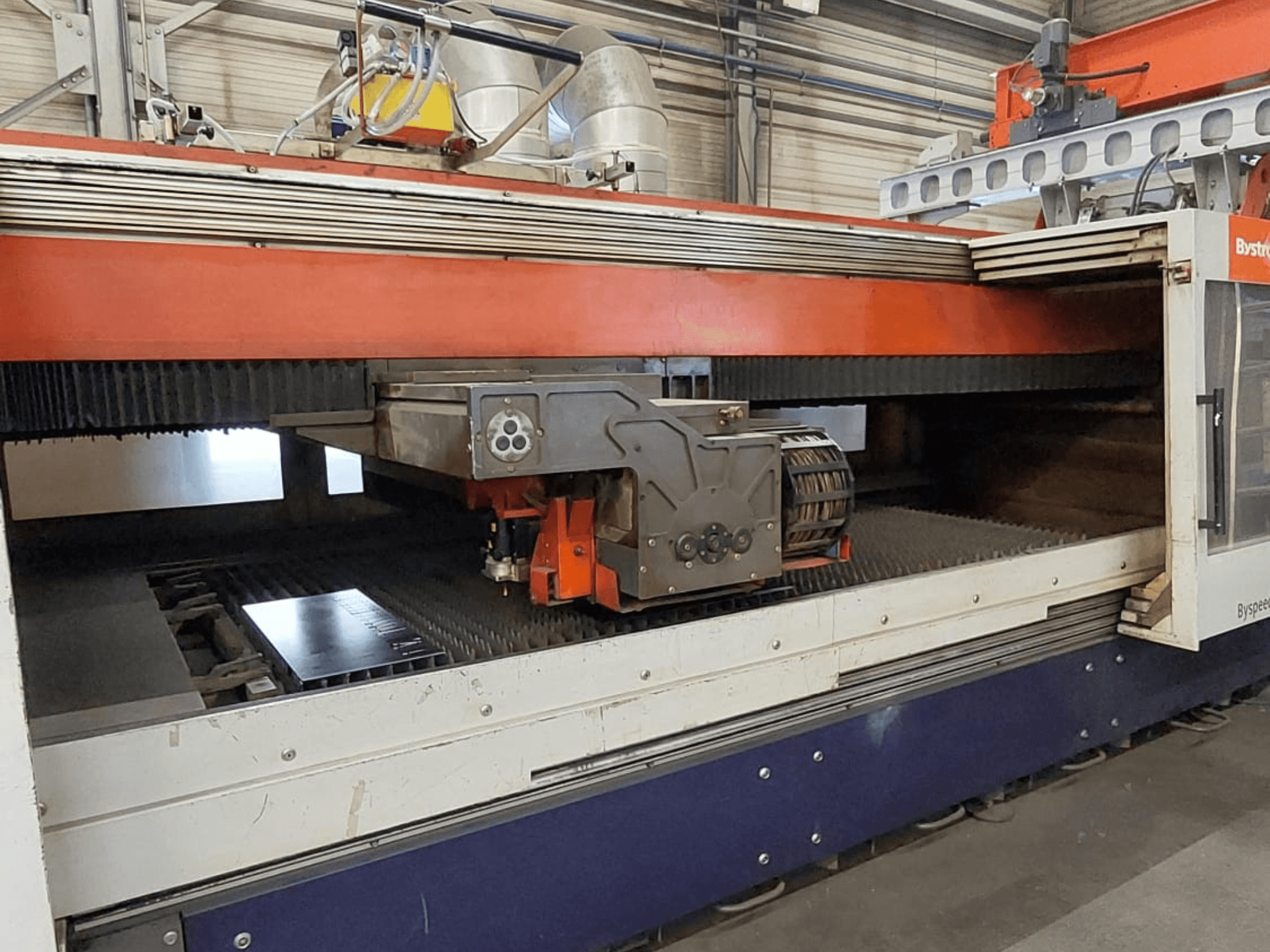 Bystronic BySpeed 3015 CO2-laserleikkauskone, etunäkymä, jossa näkyy leikkuupää ja metallilevy leikkuualustalla.