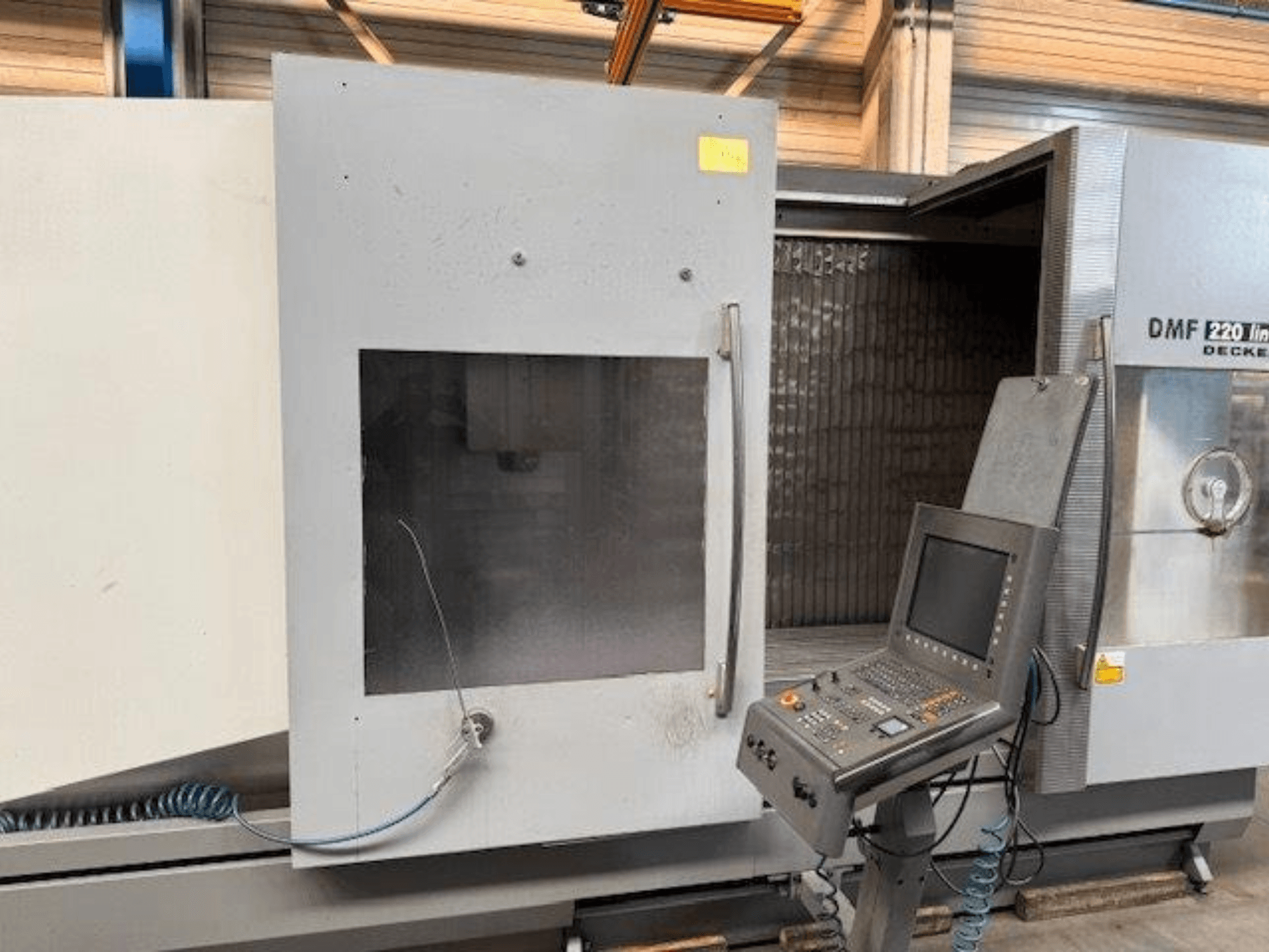 DECKEL MAHO DMF 220 Linear vertikaalisen työstökeskuksen etukuva, jossa näkyy ohjauspaneeli ja avoin koneen ovi.