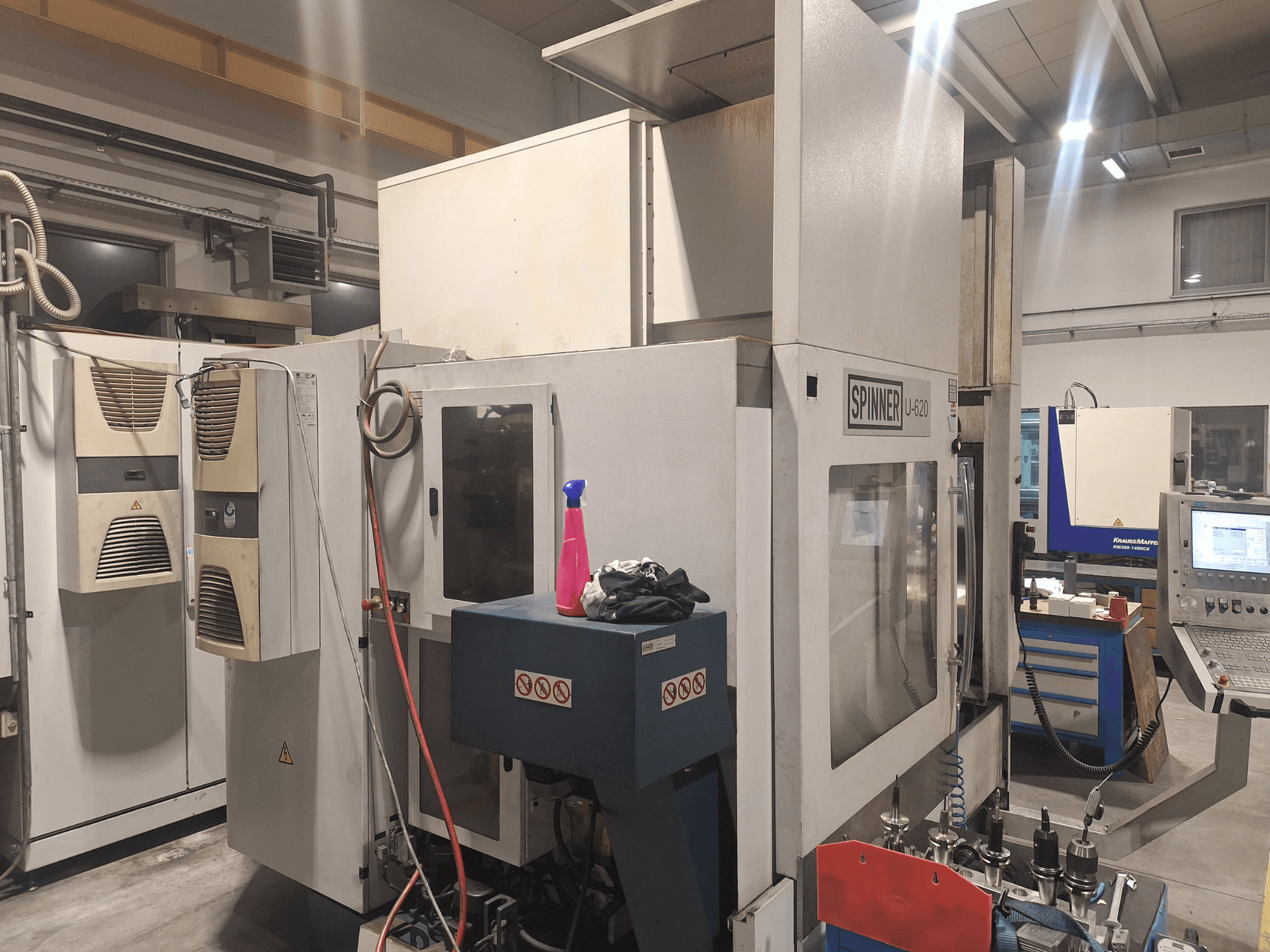 Spinner U-620 CNC-kone edestäpäin työpajassa, ohjauspaneeli ja erilaisia työkaluja läheisellä työpöydällä.
