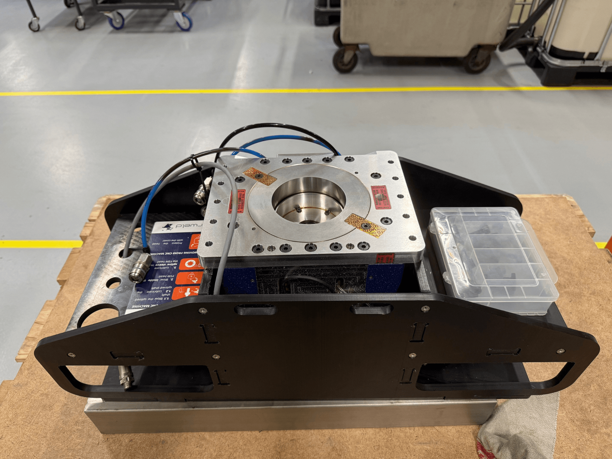 Koneistettu metallikomponentti, jossa on siniset kaapelit, lisävarustekotelo ja litteä pohja, kuvassa ylhäältäpäin, ihanteellinen mekaanisiin sovelluksiin.