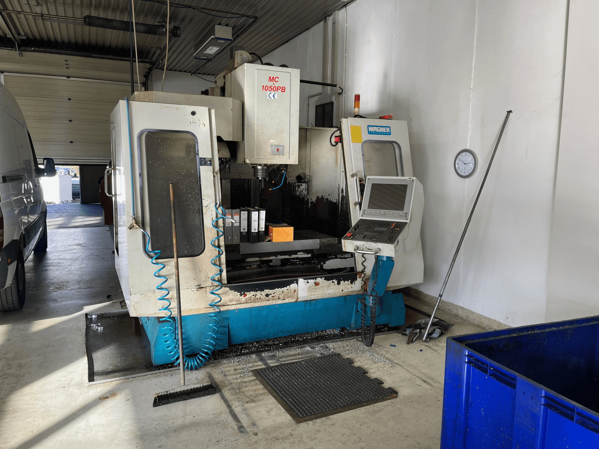WAGNER MC 1050PB CNC-kone työpajassa, etukuva, ohjauspaneeli ja työalue; sininen ilmaletku ja puhdistustyökalut näkyvissä.