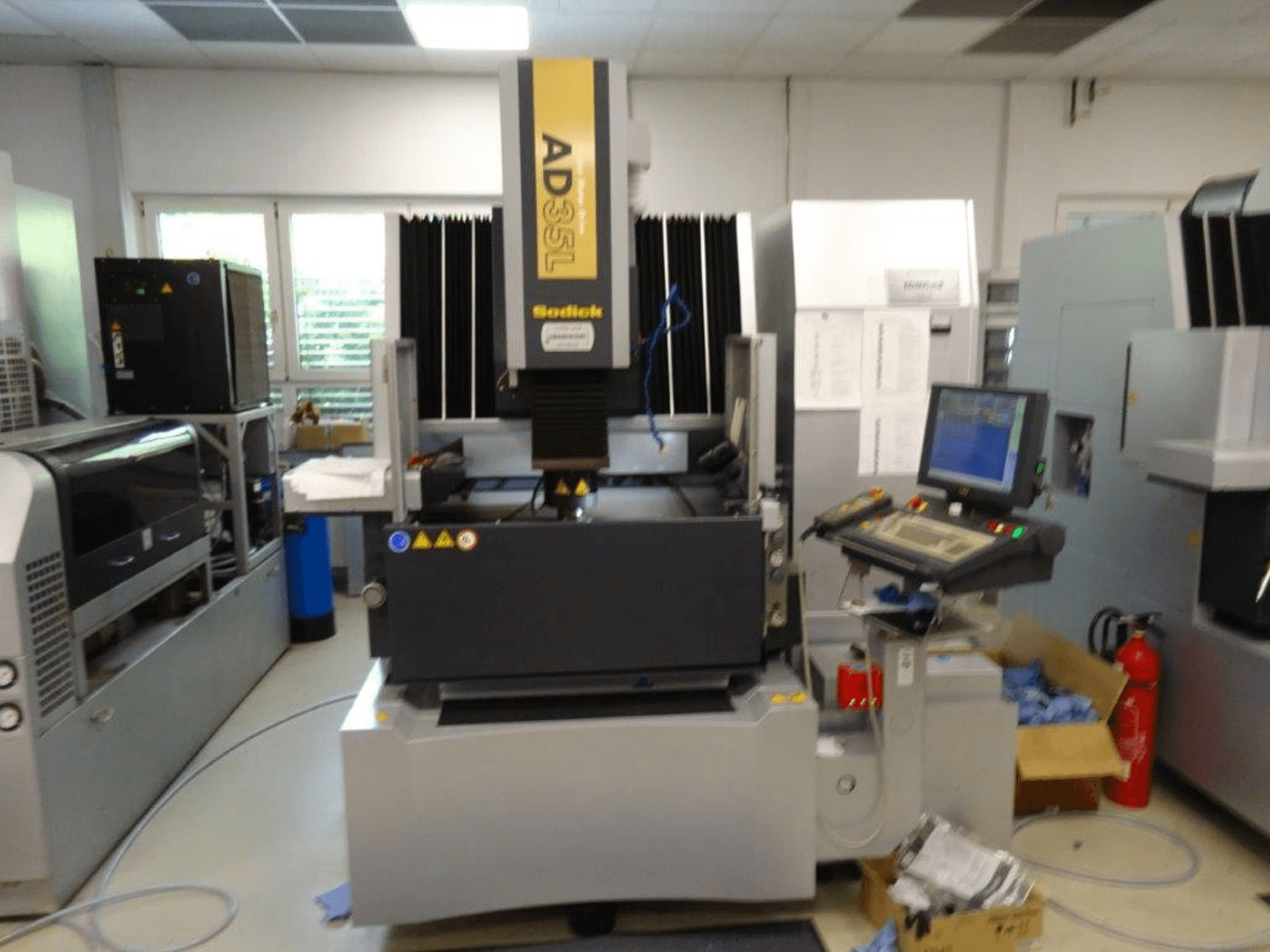 Sodick AD35L CNC-kone edestäpäin, jossa on ohjauspaneeli, jäähdytysyksikkö ja turvamerkit.