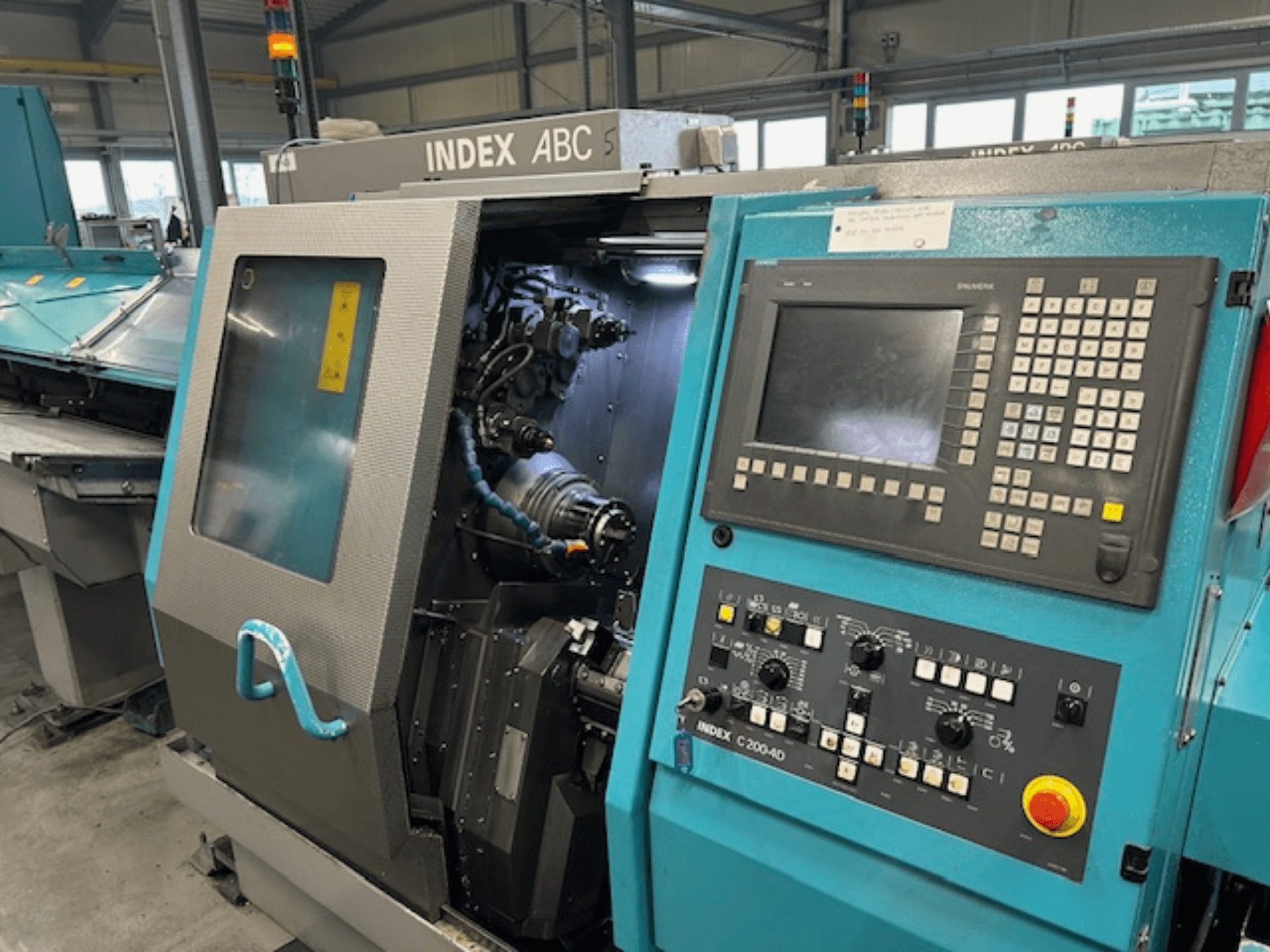 INDEX C200-AD CNC-sorvin etukuva, jossa on ohjauspaneeli, näkyvissä olevat sisäiset komponentit ja turvavarusteet.