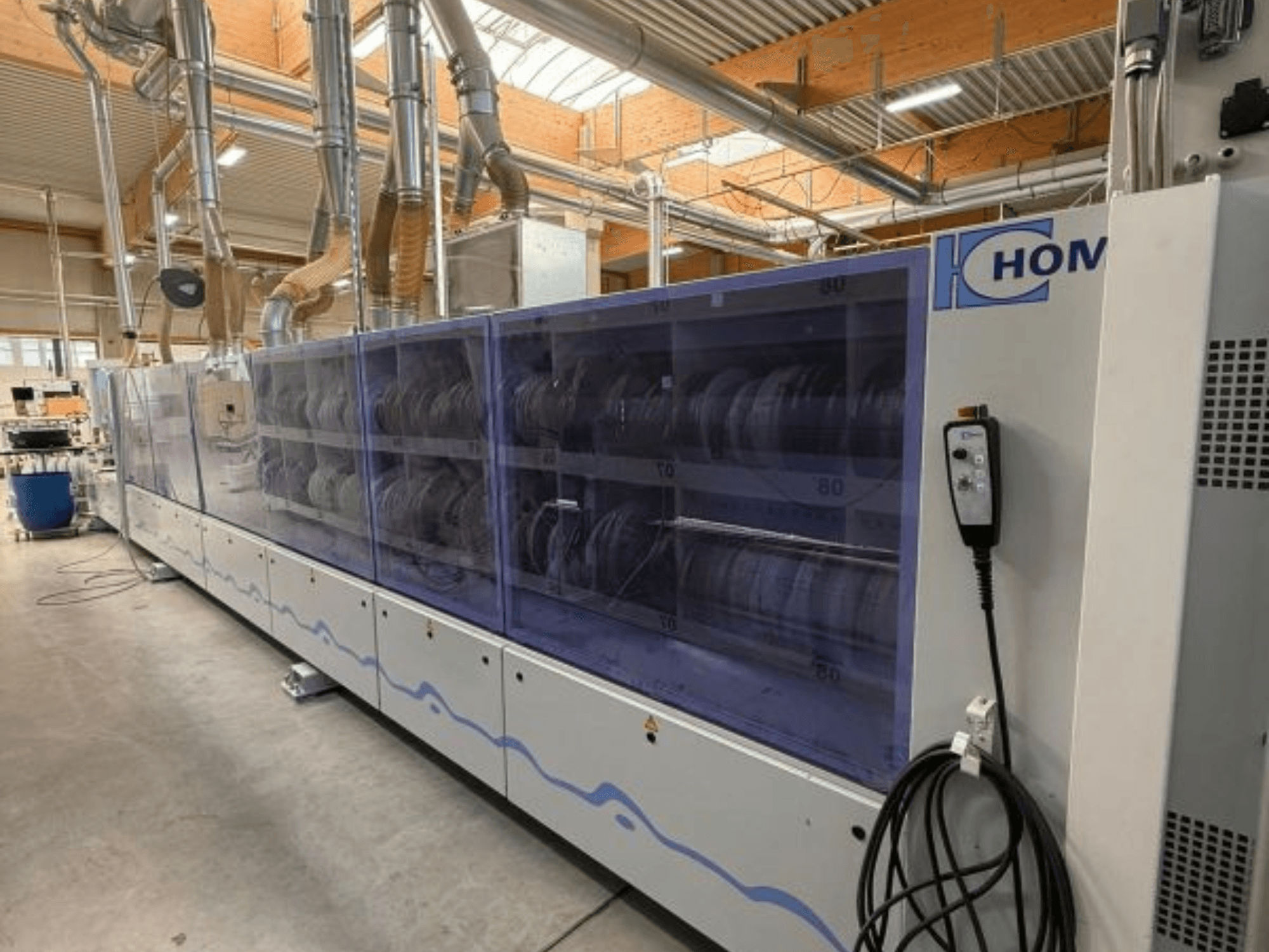 HOM-teollisuuspesukone, etukuva, jossa on läpinäkyvä paneeli, jossa näkyy astioita; ohjauspaneeli, jossa on painikkeita sivulla.