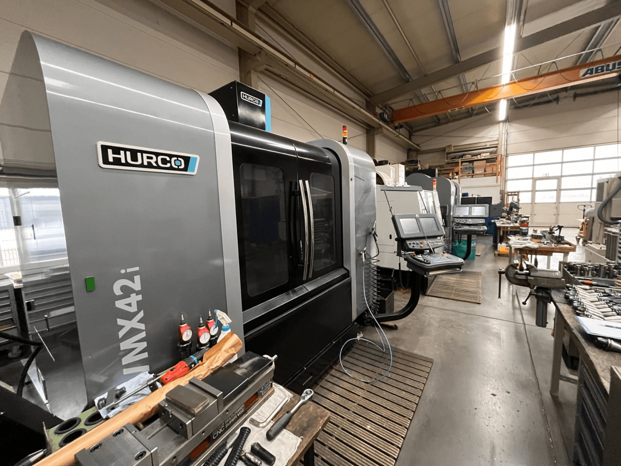 Hurco VMX42i CNC-kone työpajassa, etukuva. Ominaisuudet ohjauspaneeli, harmaa runko ja teollinen ympäristö.