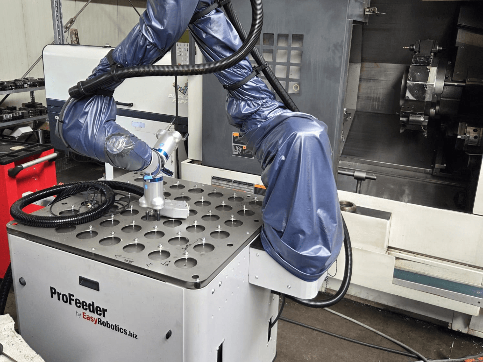 Yhteistyörobotti EASYROBOTICS ProFeeder etukuvasta, jossa robottivarsi on sijoitettu rei'itetyn metallipöydän päälle.