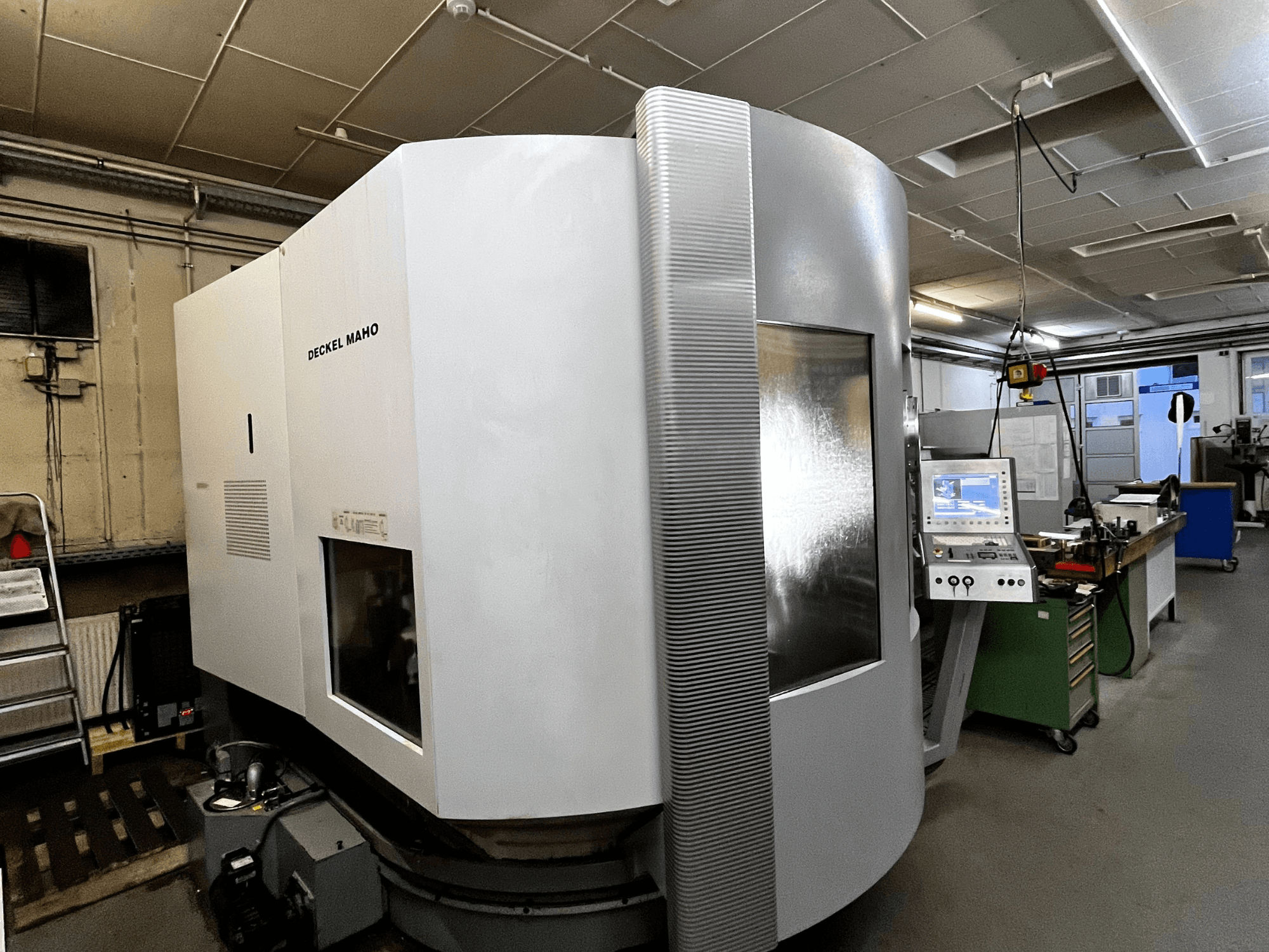 Deckel Maho CNC-kone, etukuva, valkoinen ulkokuori, ohjauspaneeli näkyvissä, työpajakäytössä.