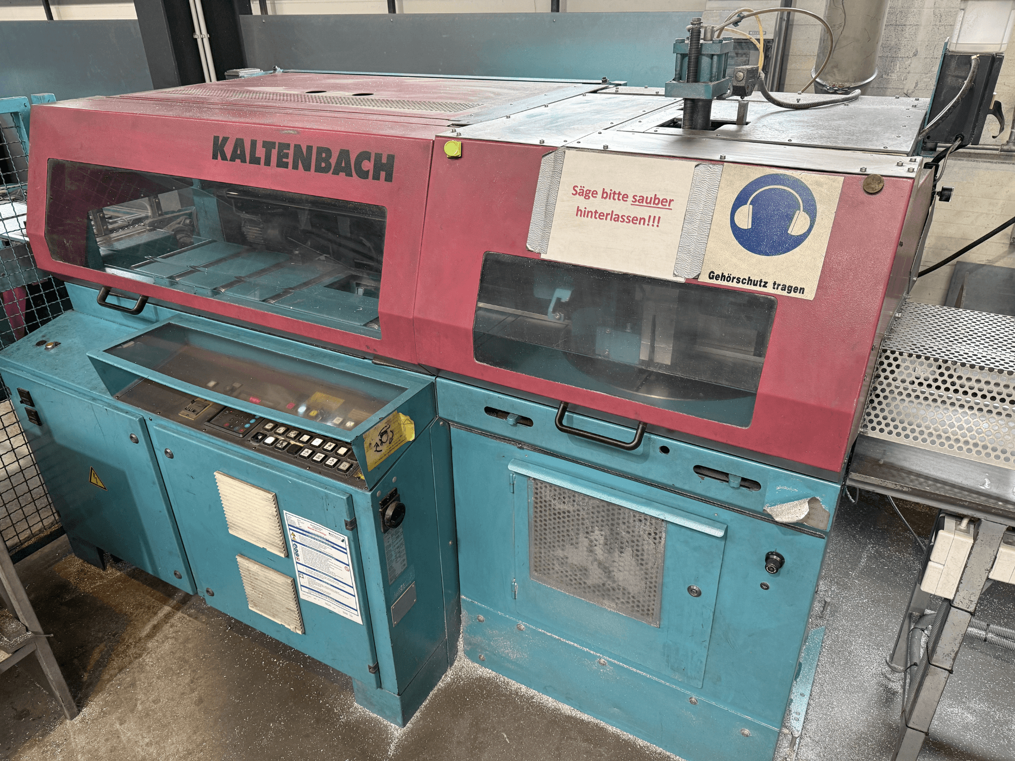 KALTENBACH-teollisuusleikkauskone, etukuva, jossa on ohjauspaneeli ja kuulosuojainten turvamerkki.