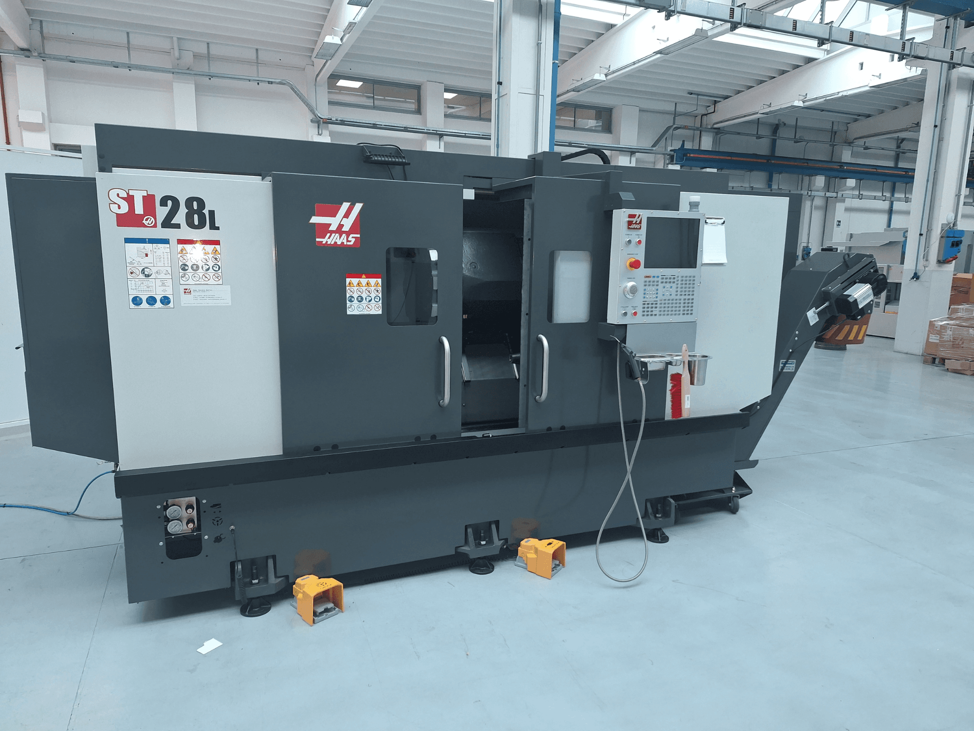 Haas ST-28L -vaakasuoran sorvin sivukuva, jossa näkyvät ohjauspaneeli, käyttöpainikkeet ja turvallisuusmerkinnät.