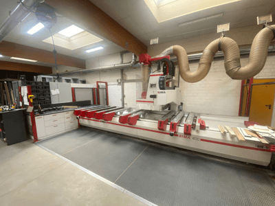 BIMA 400 CNC-kone edestä katsottuna, punavalkoinen muotoilu ja pölynpoistojärjestelmä.