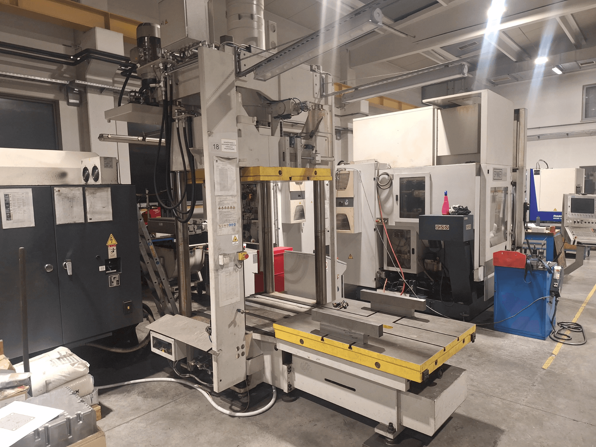 Synergicin vaakajyrsin, etukuva; siinä on leveä pöytä ja erilaisia ohjauspaneeleita, työpajassa.