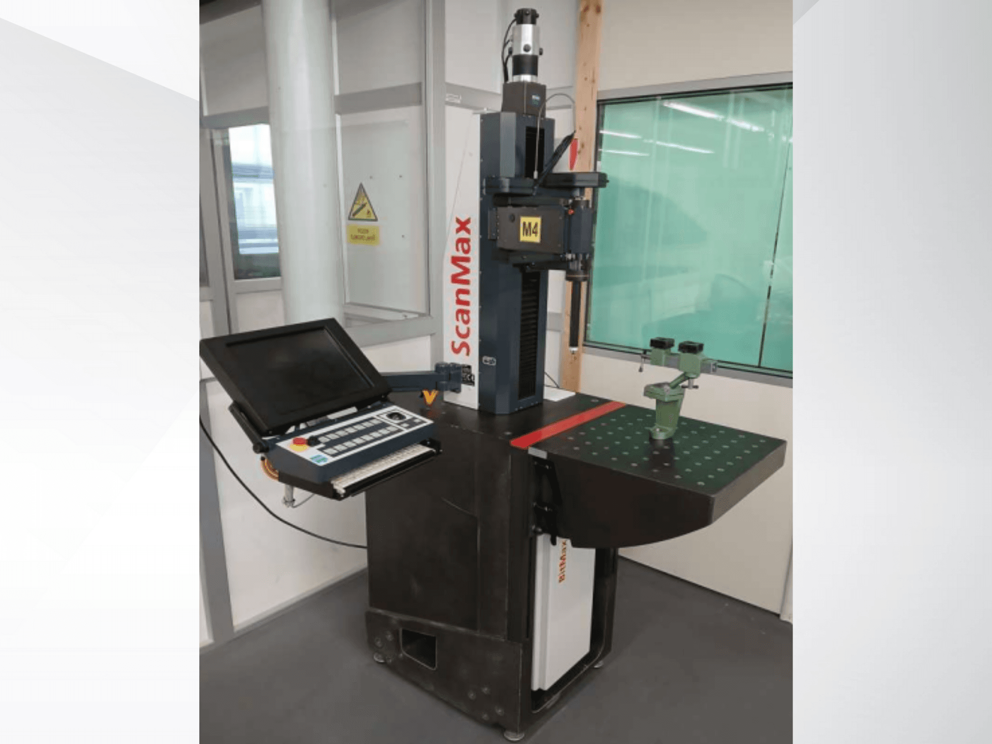 ScanMax M4 -mittauskone, etukuva, jossa ohjauspaneeli ja vihreä kalibrointikiinnike pistemäisellä työpöydällä.