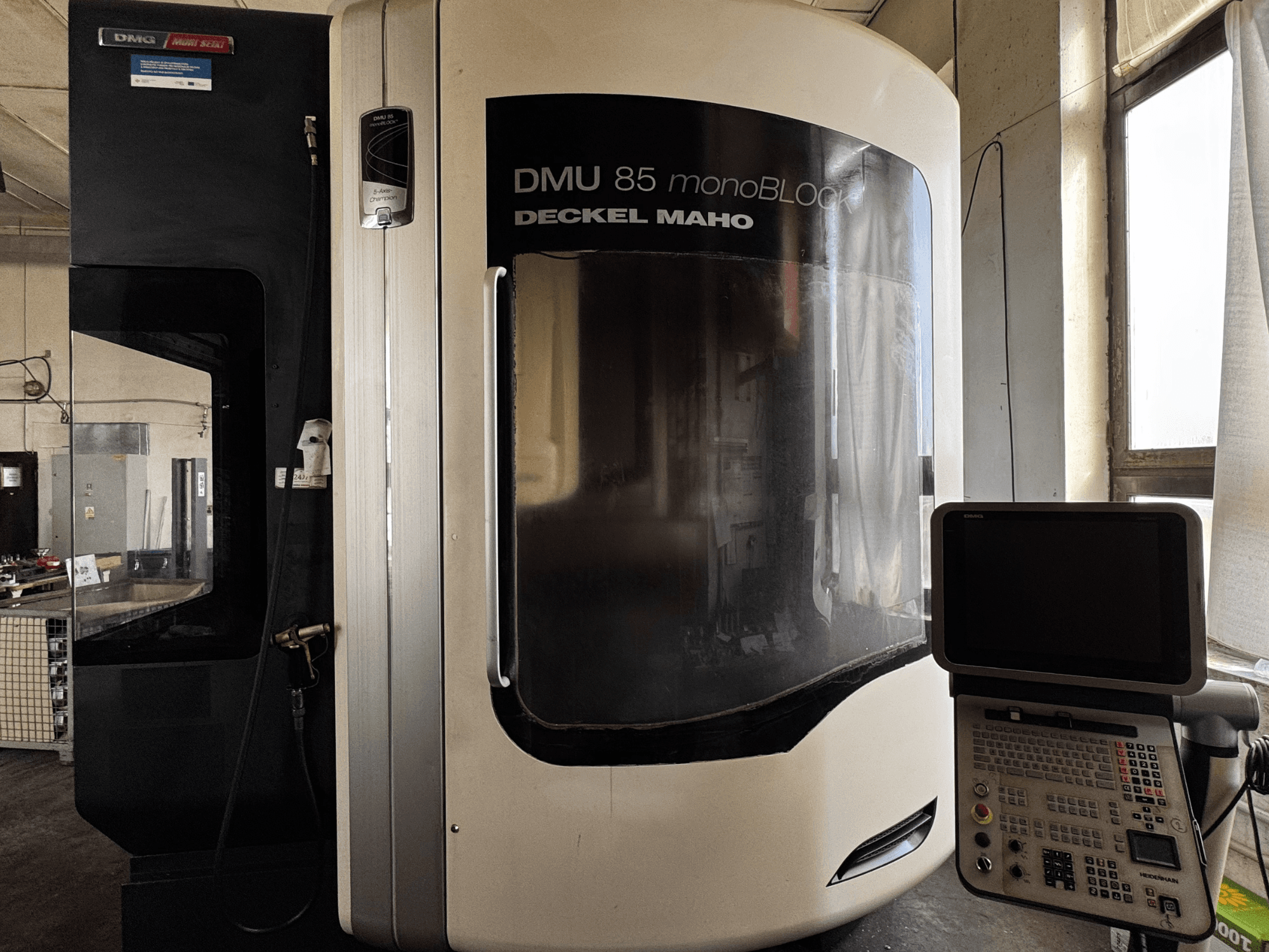 DMG MORI DMU 85 monoBLOCK -pystytyöstökeskus, etukuva, jossa on ohjauspaneeli ja suuri katseluikkuna.