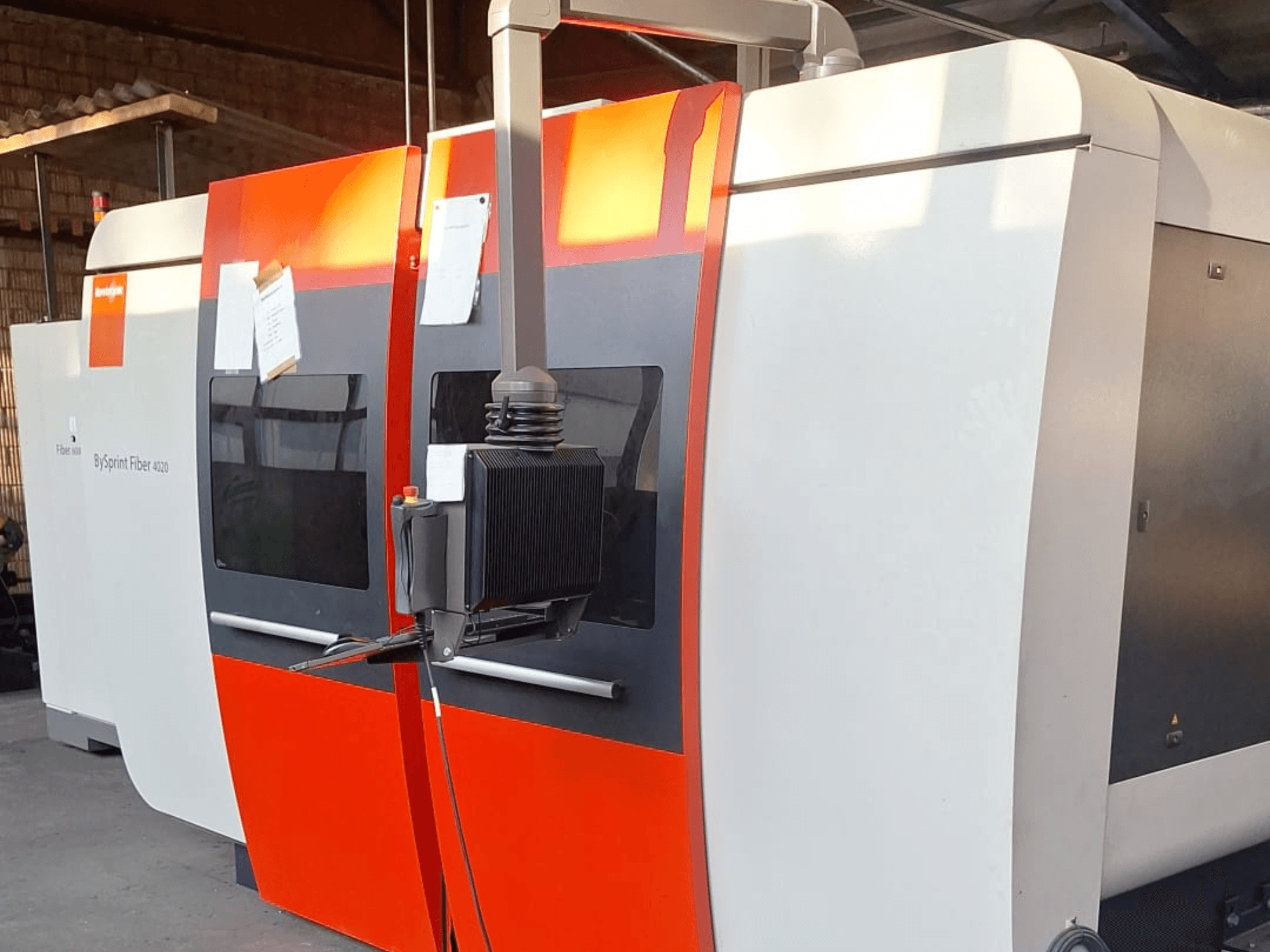 BySprint Fiber 4020 -laserleikkauskone, sivukuva, punainen ja valkoinen ulkopinta, yksityiskohtainen ohjauspaneeli näkyvissä.