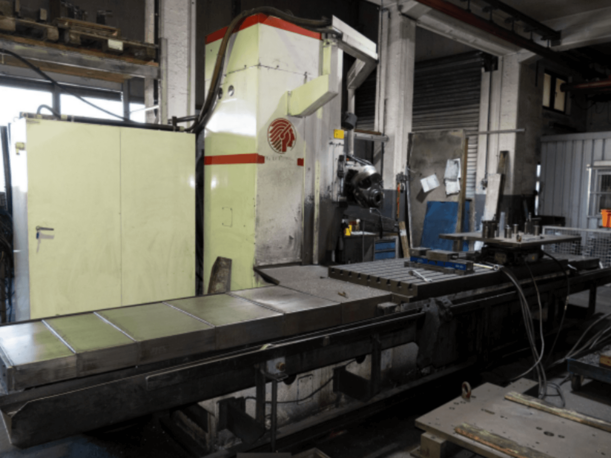 Suurella pöydällä varustettu teollisuusjyrsin, sivukuva, jossa esitellään hallintalaitteita ja lisälaitteita työpajassa.