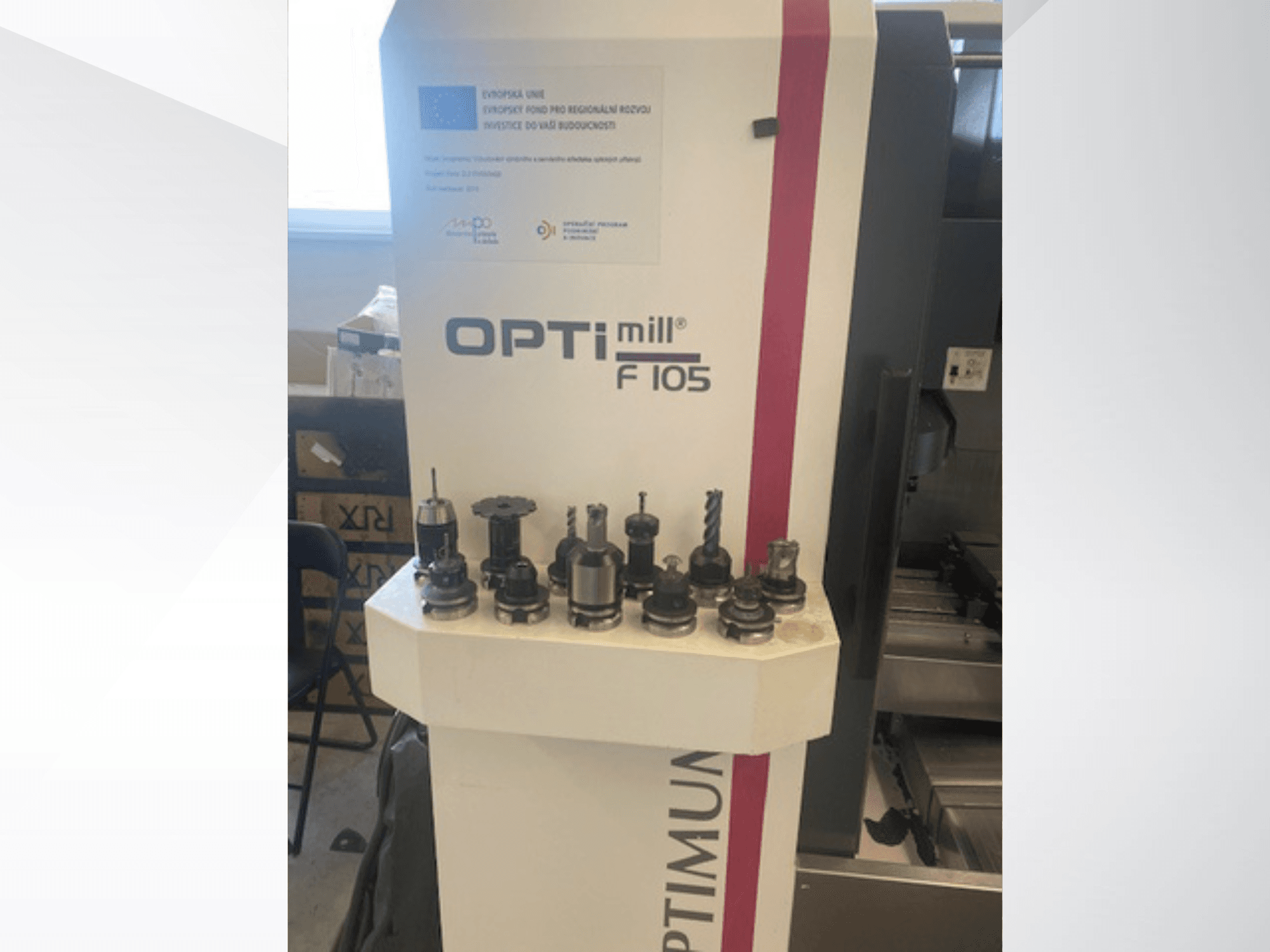 Optimum Optimill F105 -pystykoneistuskeskus edestä katsottuna; sivulla näkyy erilaisia siihen kiinnitettyjä työkaluja.