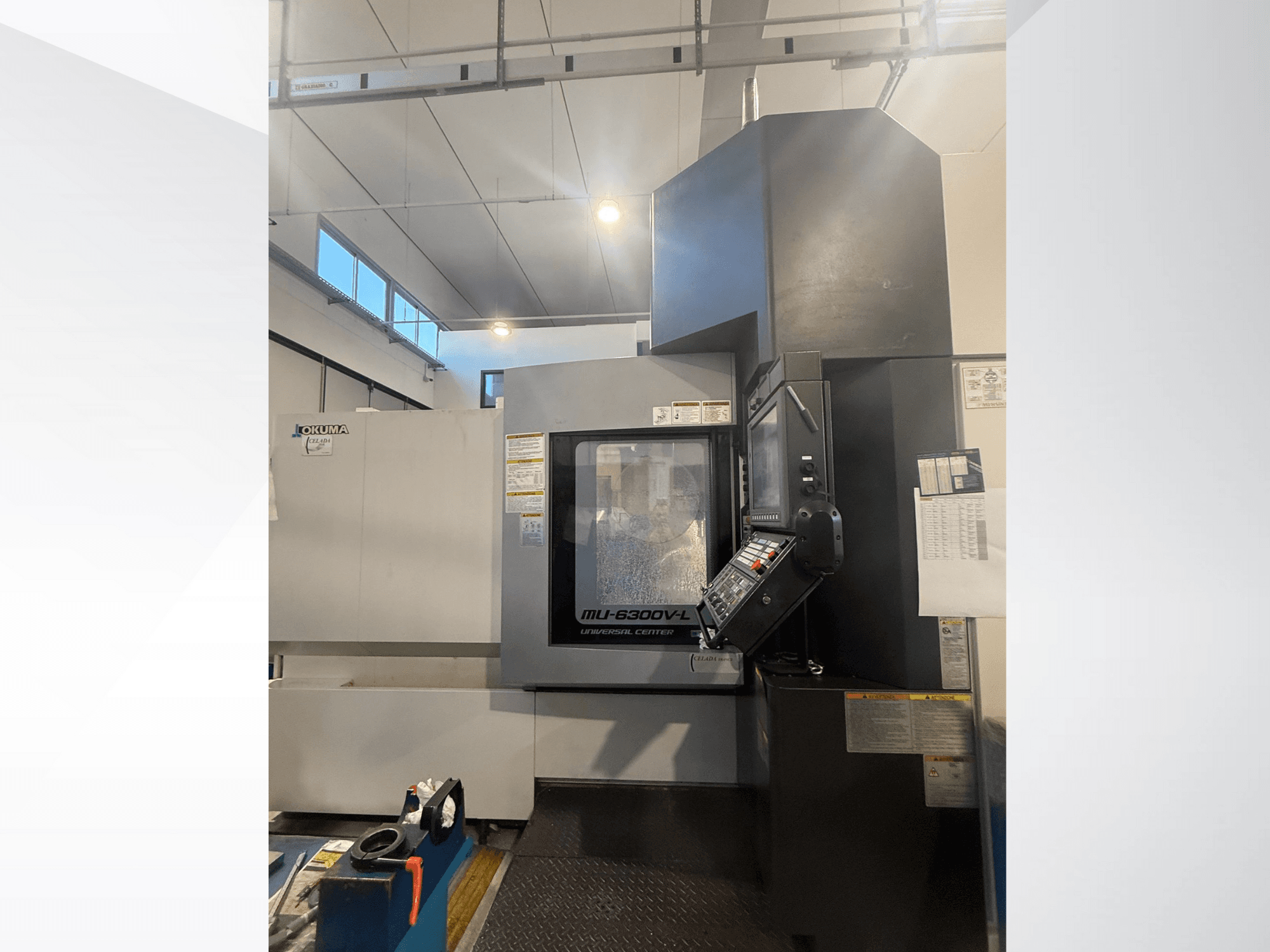Okuma MU-6300V-L CNC-kone edestä katsottuna, jossa näkyy ohjauspaneeli ja turvatarrat.