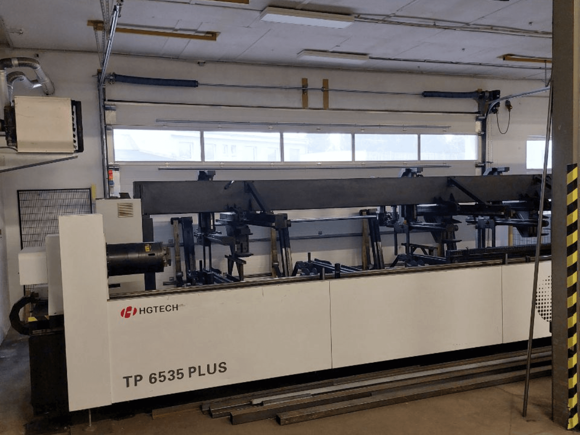 HGTECH TP 6535 PLUS, etukuva suuresta teollisuuskoneesta, jossa on useita käsivarsia tarkkuutta vaativaan valmistukseen, työpajassa.
