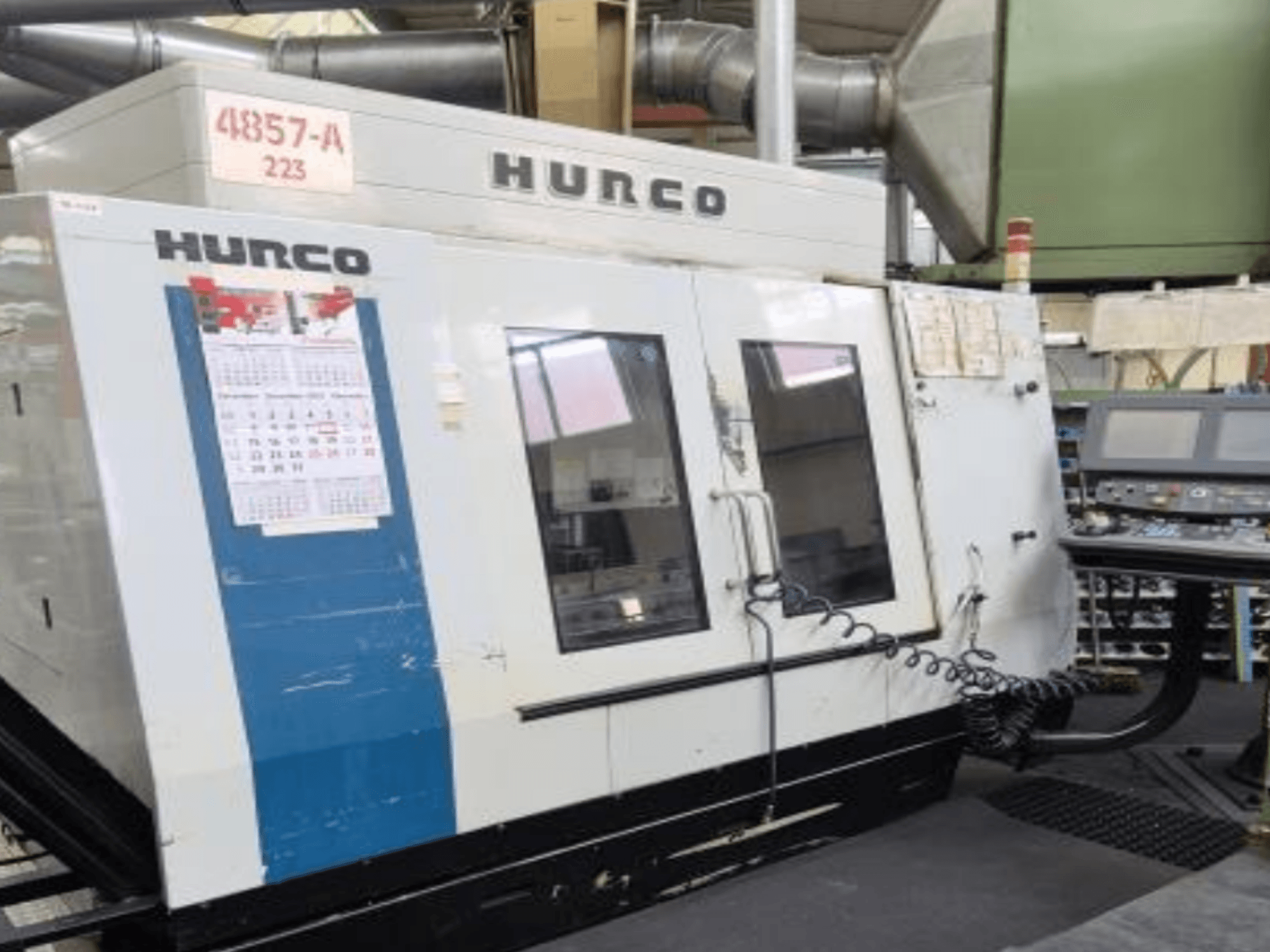 Hurco VMX 42 -pystytyöstökeskus etukuvassa, jossa on ohjauspaneeli, kalenteri ja metalliset ulkosivut.