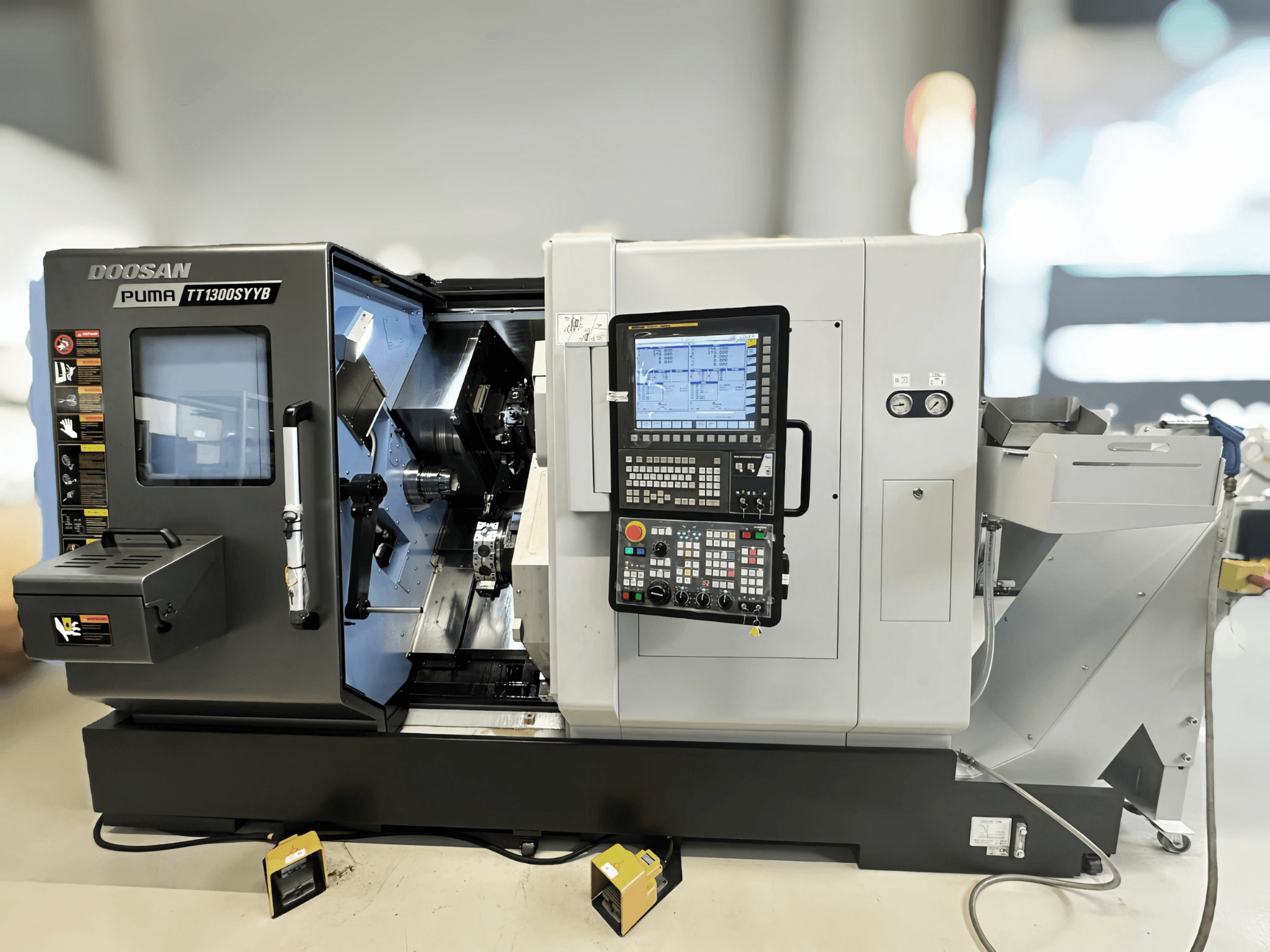 Doosan Puma TT1300SYYB -kääntökeskus sivukuvassa, jossa näkyy ohjauspaneeli ja koneen sisätilat sekä työkalut näkyvissä.