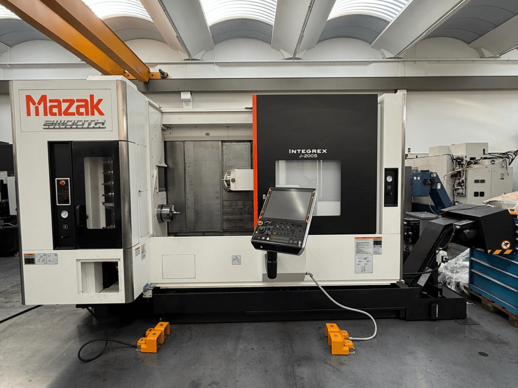 Mazak INTEGREX J-200 S -jyrsintäsorvauskeskus edestä katsottuna, jossa on ohjauspaneeli ja työstöalue, asetettu tehtaan lattialle.