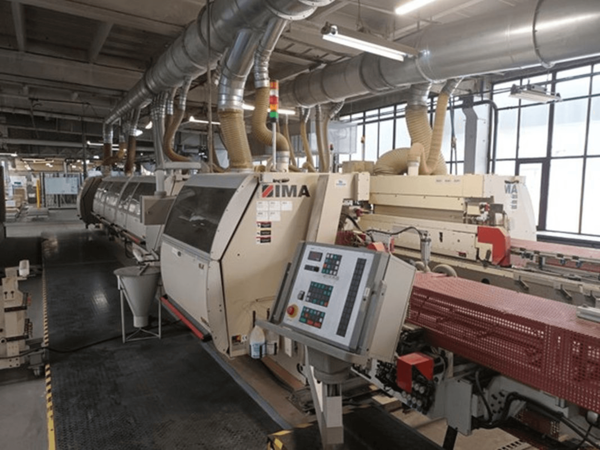 IMA-teollisuuskoneet tehdasympäristössä, etukuva, jossa on ohjauspaneelit ja pölynpoistoputket.