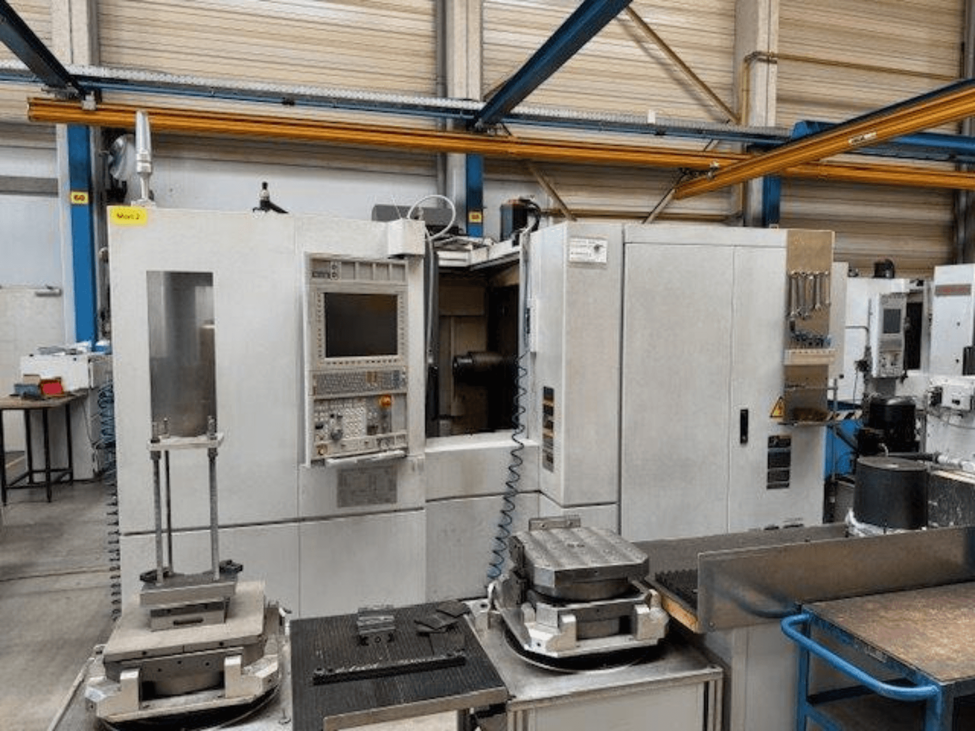 MORI SEIKI NH4000 DCG vaakatasossa olevan työstökeskuksen etukuva, jossa on ohjauspaneeli ja työkappaleita pöydällä.