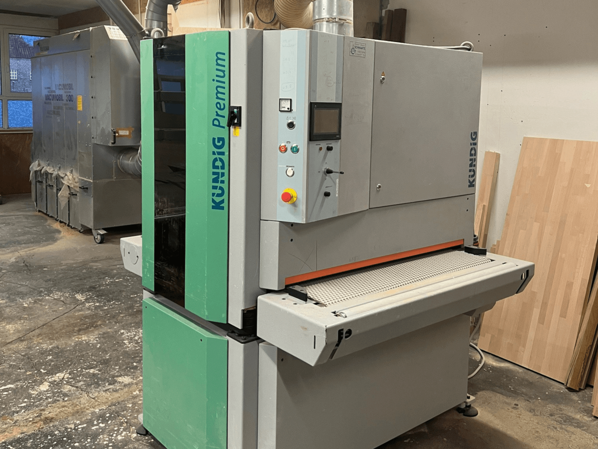 Kundig Premium-1 1100K -hihnahiomakone harmaana ja vihreänä, kuvassa sivukuva, jossa ohjauspaneeli ja hiomahihna näkyvissä.