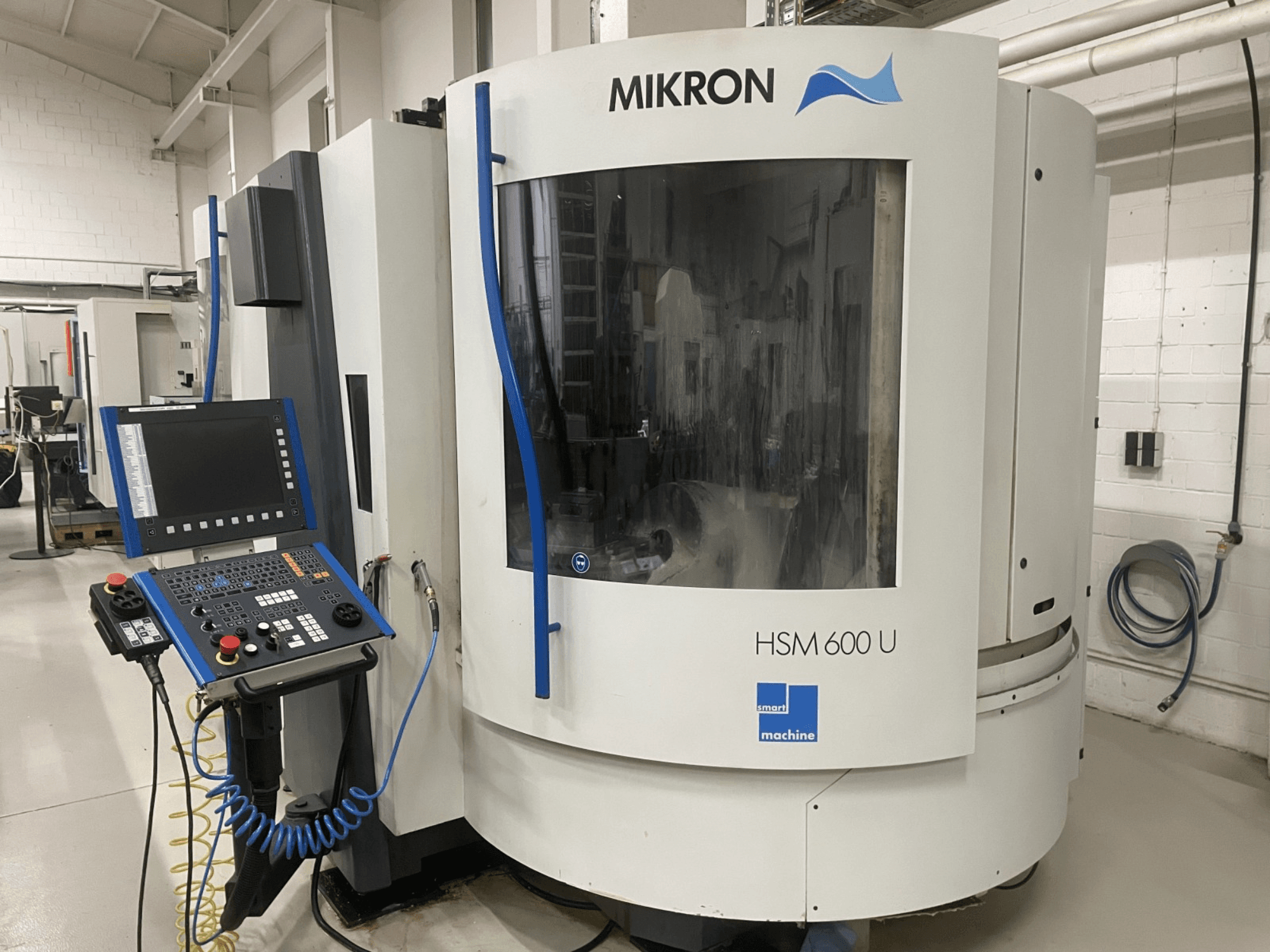 MIKRON HSM600U -pystytyöstökeskus edestä kuvattuna, jossa on toiminnallinen ohjauspaneeli ja suuri katseluikkuna.