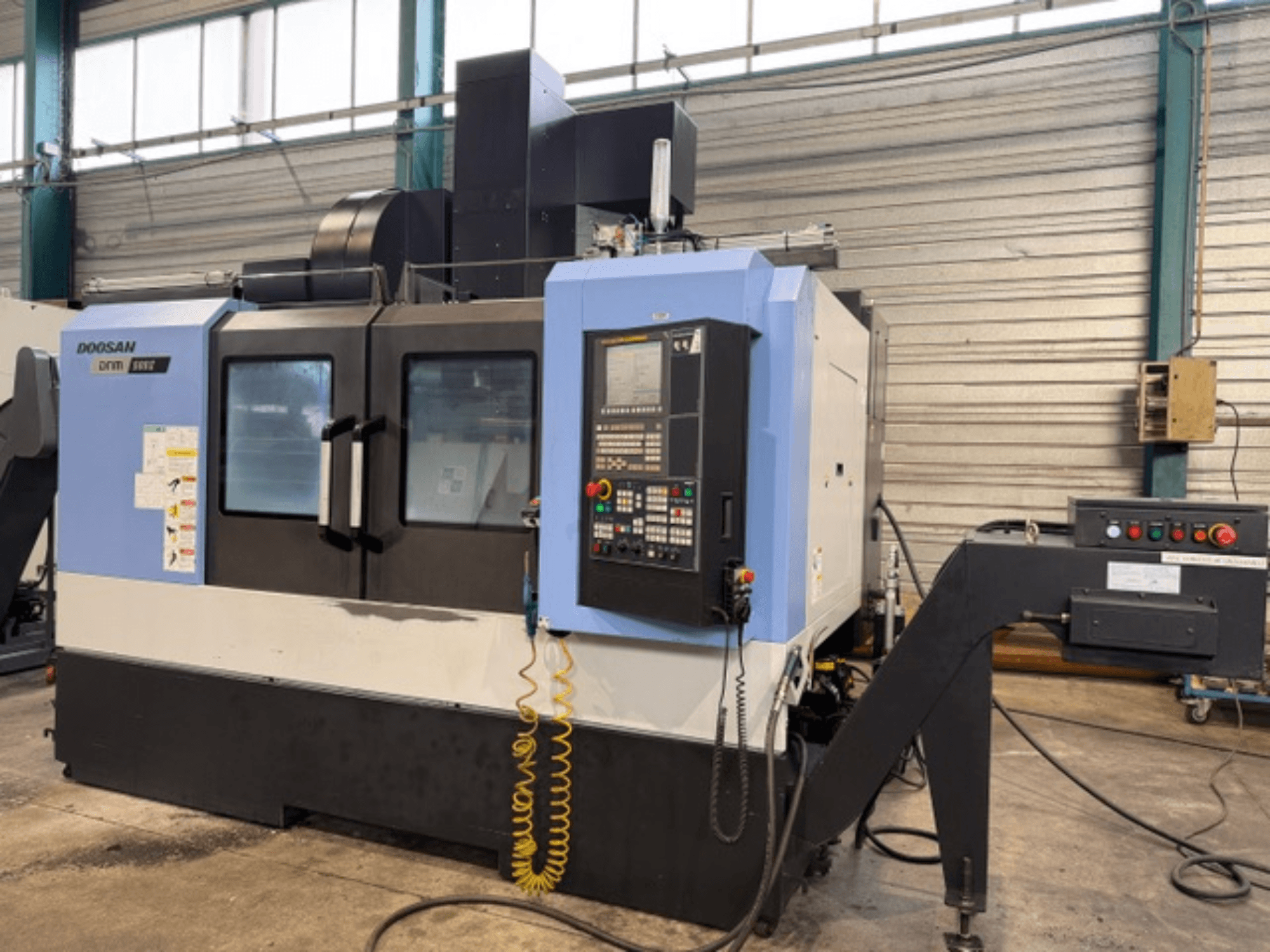 Doosan DNM 500II CNC-jyrsinkone etukuvassa, jossa on ohjauspaneeli ja työkalunpidin, tehdasympäristössä.
