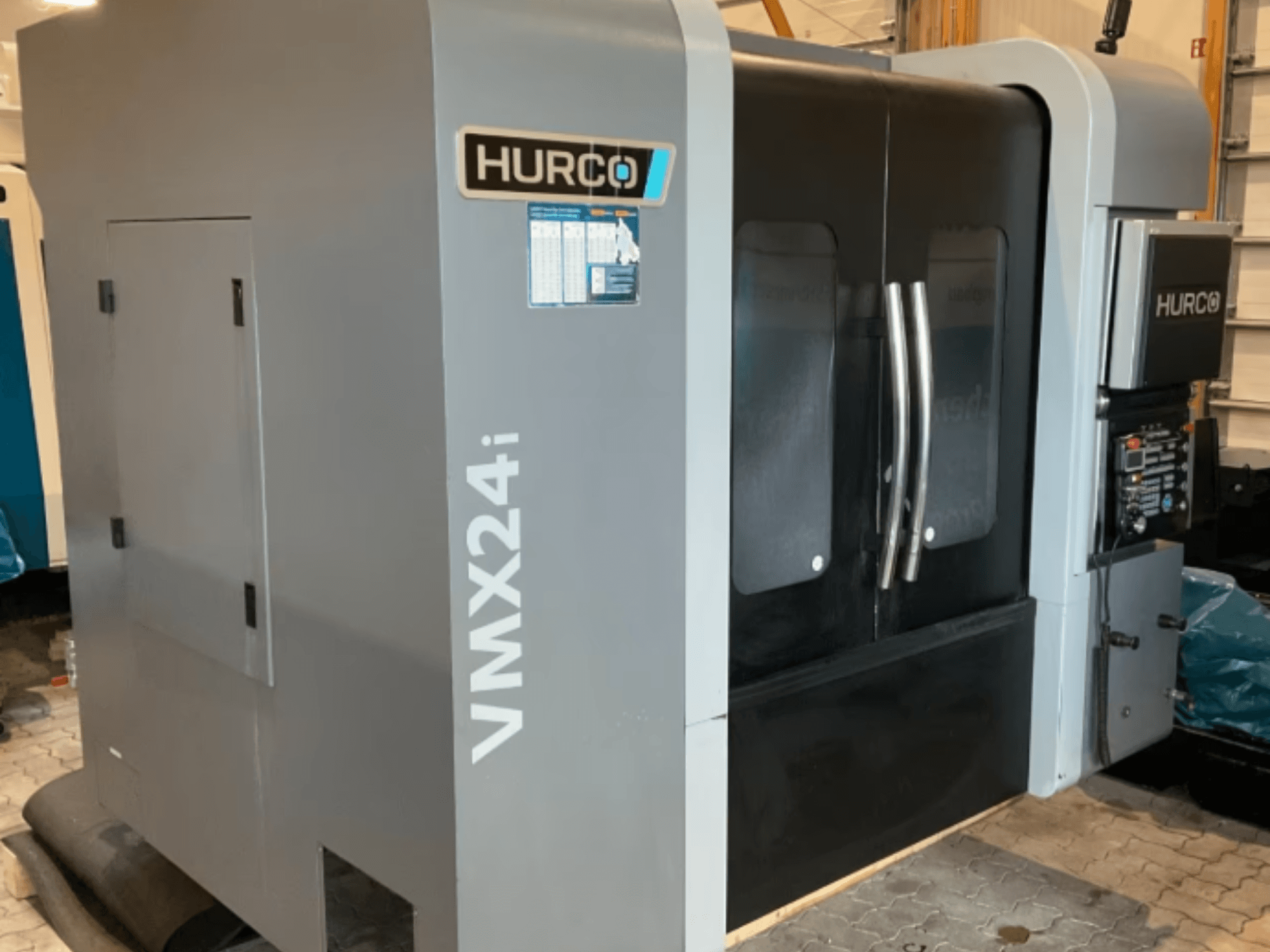 Hurco VMX 24i -pystykoneistuskeskus, etunäkymä: metallinharmaa runko, mustat paneeliluukut ja ohjauspaneeli.