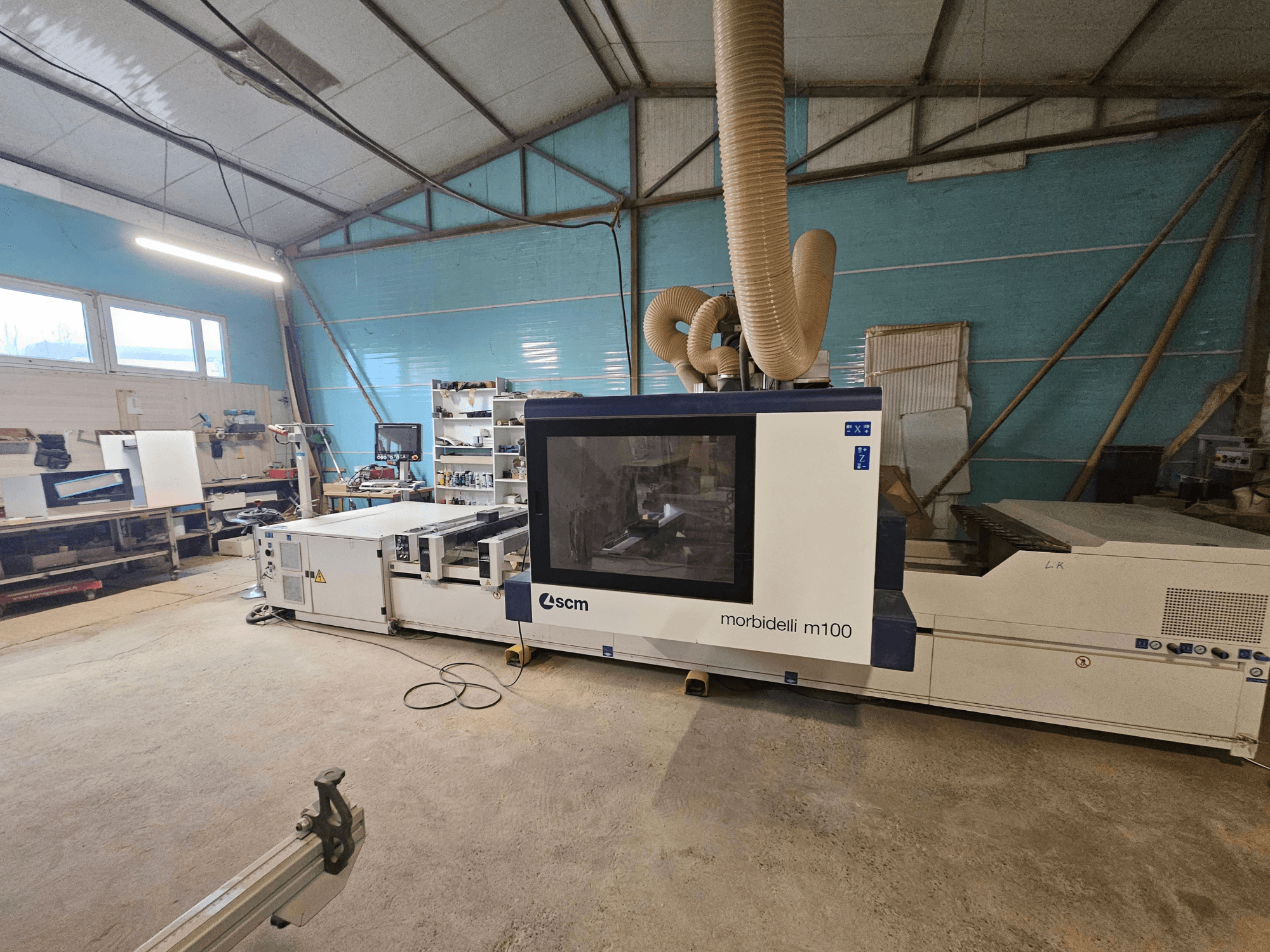 SCM Morbidelli M100 CNC-kone työpajassa, etukuva, jossa näkyy pölynpoistojärjestelmä ja ohjauspaneeli.