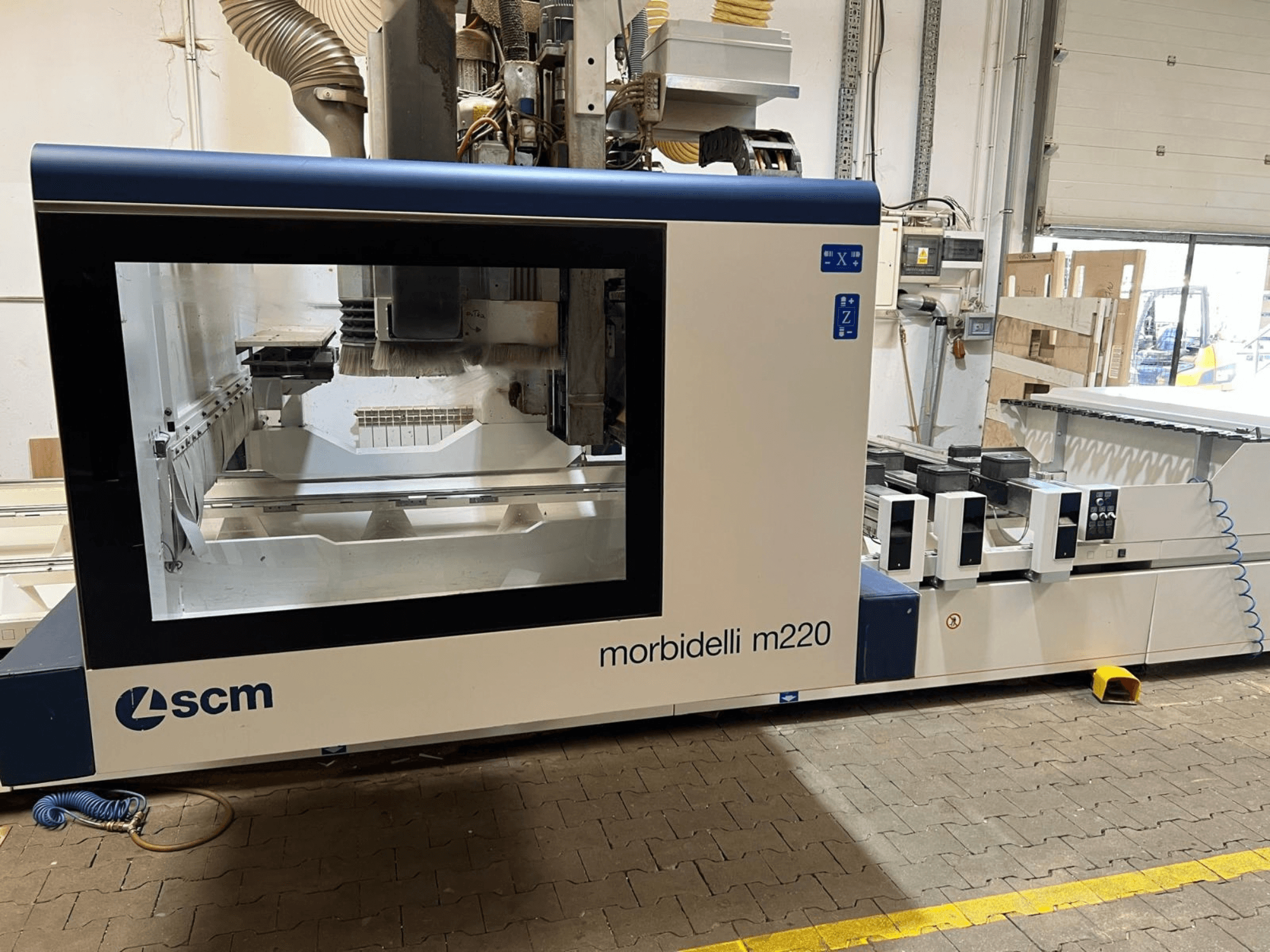 SCM Morbidelli M220 CNC-koneistuskeskus edestä katsottuna: kuvassa näkyy suuri ikkuna, ohjauspaneeli ja työstöalue.