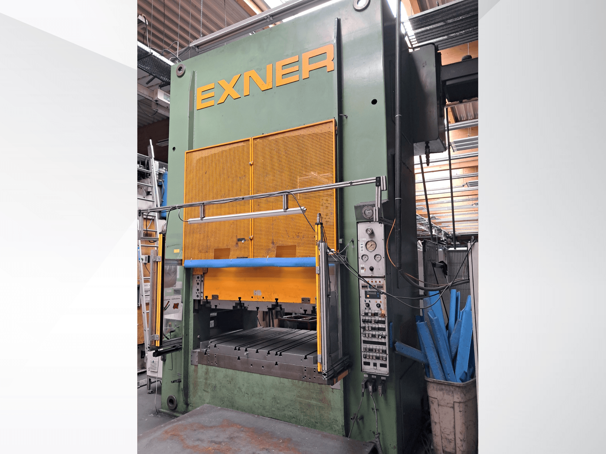 EXNER EX SBR 150 -hydraulipuristin, etunäkymä; kuvassa näkyvät ohjauslaitteet, sininen turvapalkki ja suojaverkko, asennettuna työpajaympäristöön.