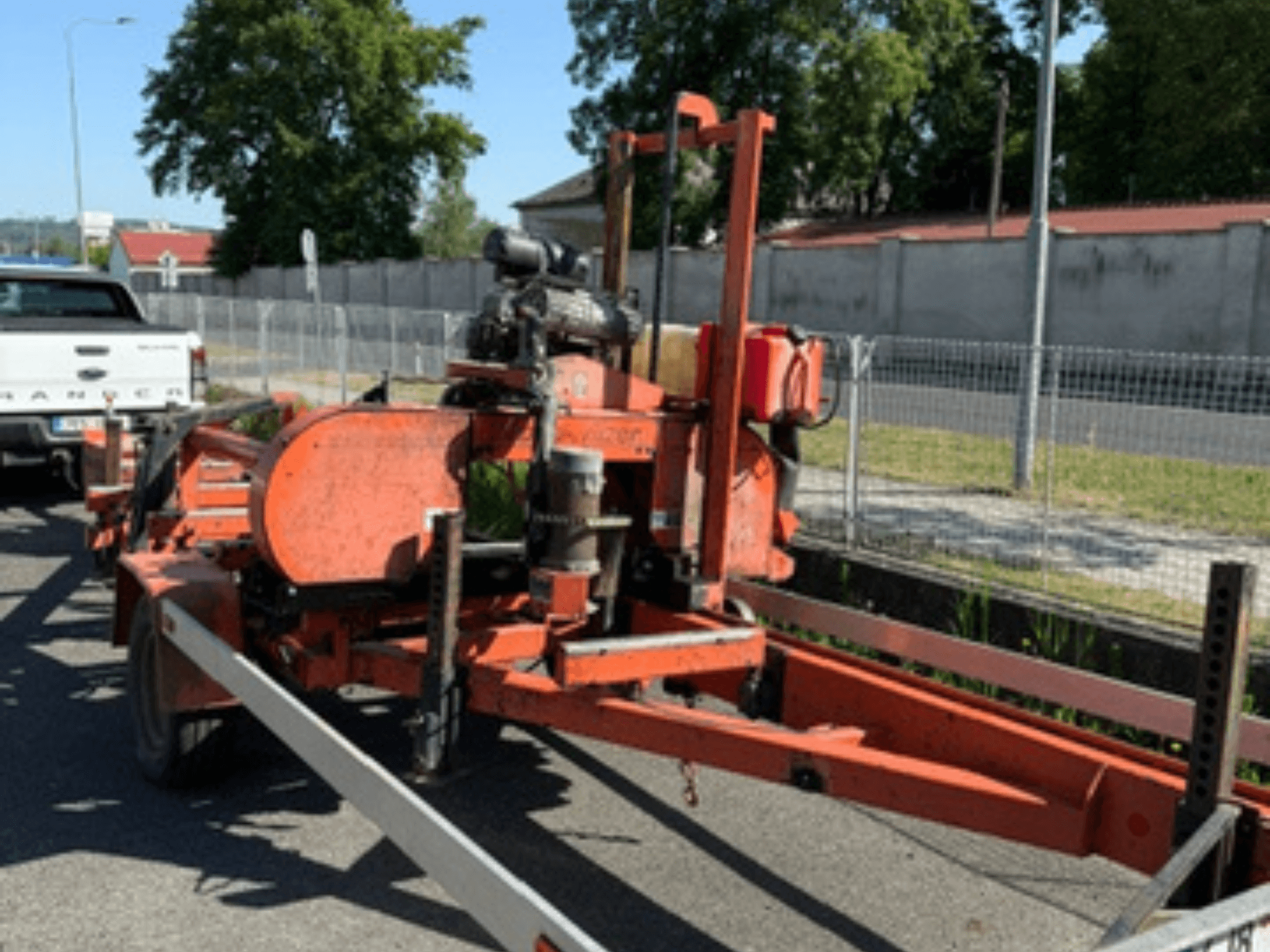 WOOD-MIZER LT40 -puunauhasaha oranssina, sivukuva perävaunulla, jossa näkyvät pyörät ja moottorin osat.