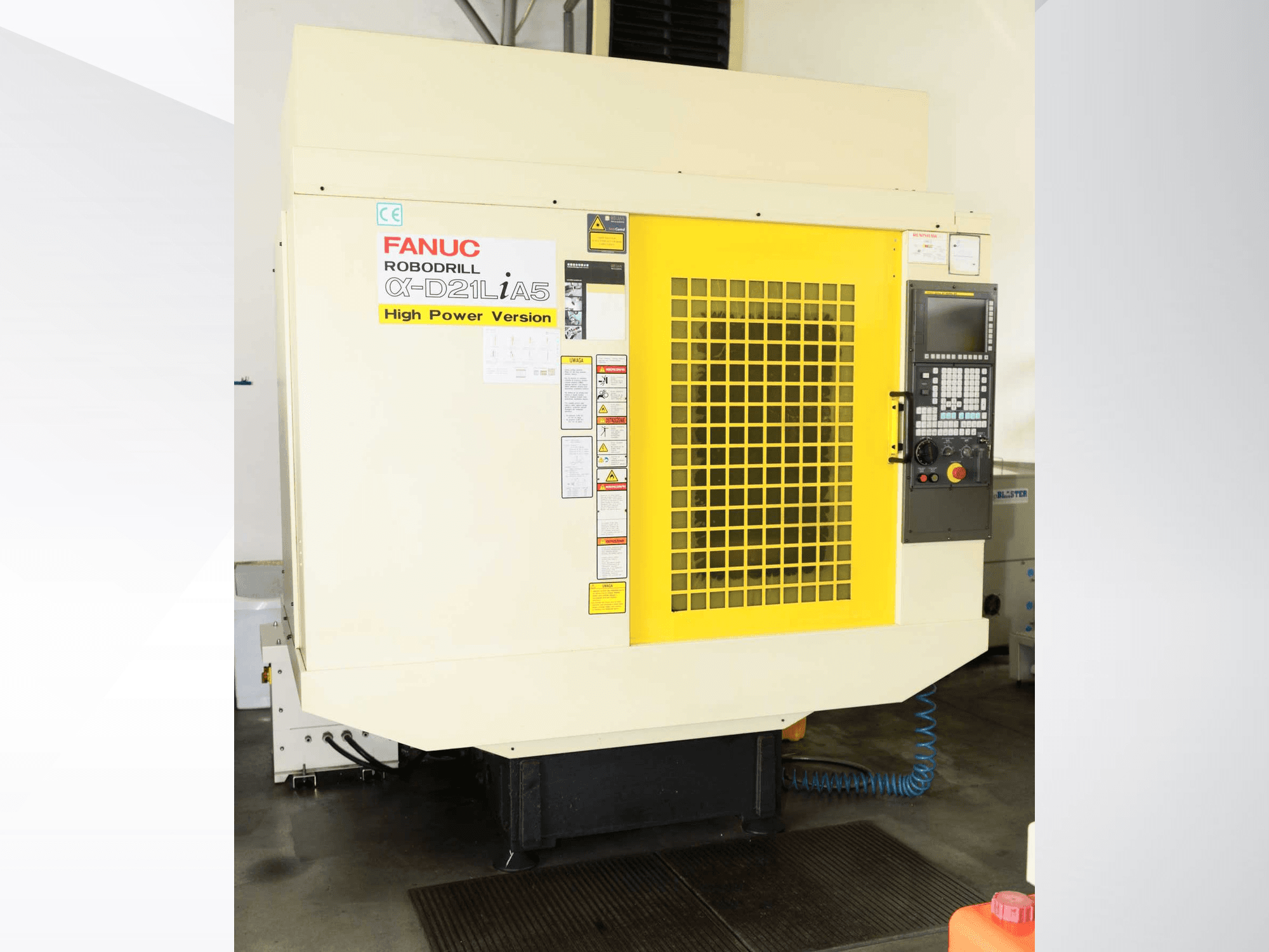 FANUC ROBODRILL α-D21LiA5 -pystykoneistuskeskus, etunäkymä, jossa näkyy keltainen suojaritilä ja ohjauspaneelin yksityiskohdat.