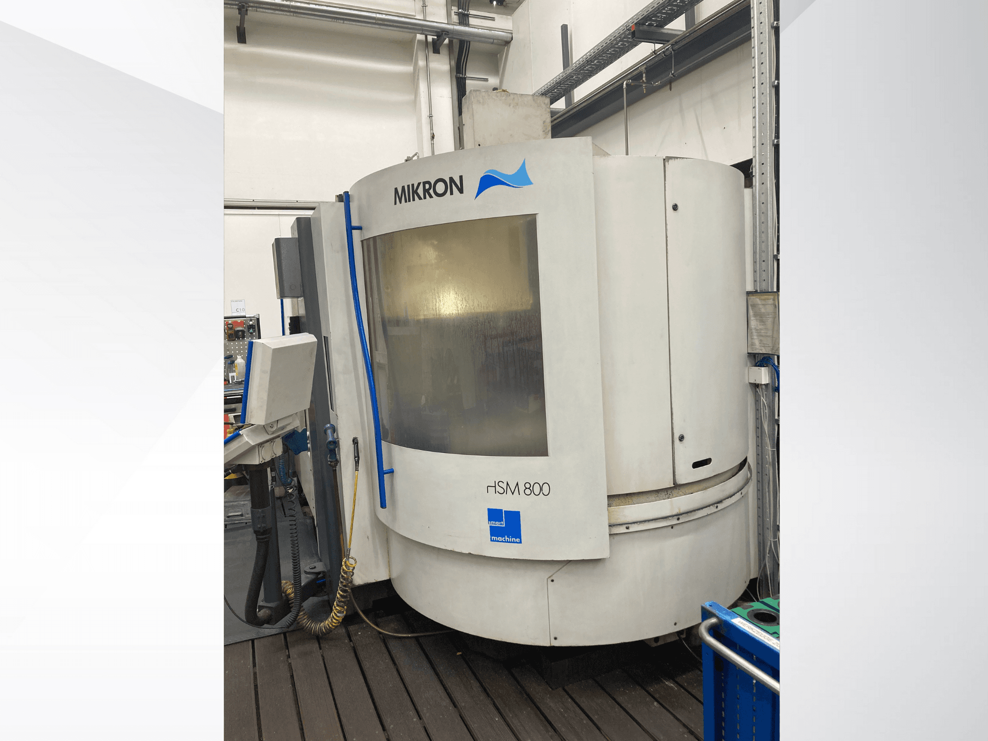 Mikron rISM 800 CNC-kone, etukuva ohjauspaneelilla, sylinterimäinen muotoilu ja siniset korostukset, asetettu työpajaympäristöön.