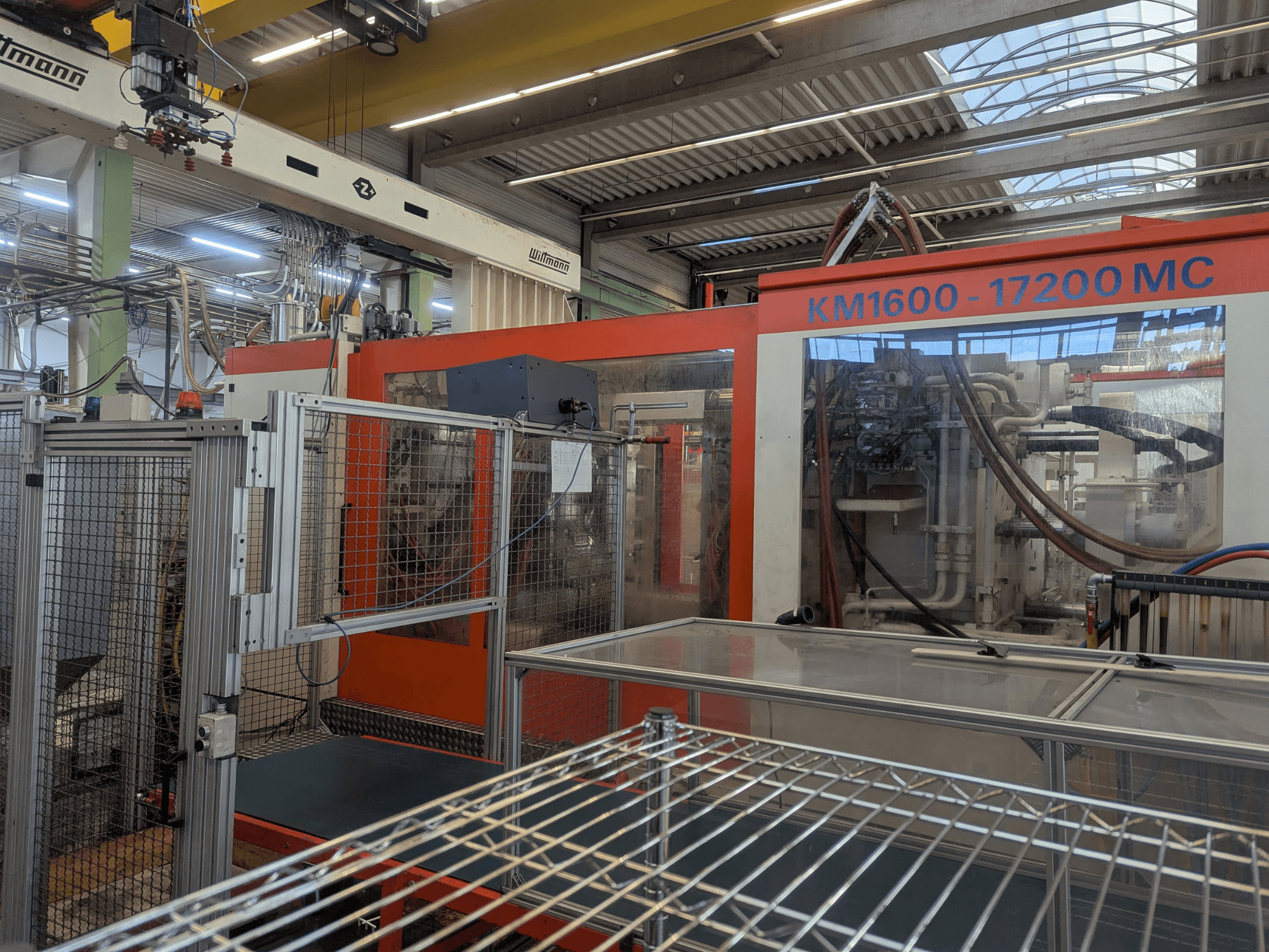 Hydraulinen ruiskuvalukone Krauss Maffei KM 1600-17200MC, etukuva, jossa näkyy ohjauspaneeli ja hydrauliikkalinjat.