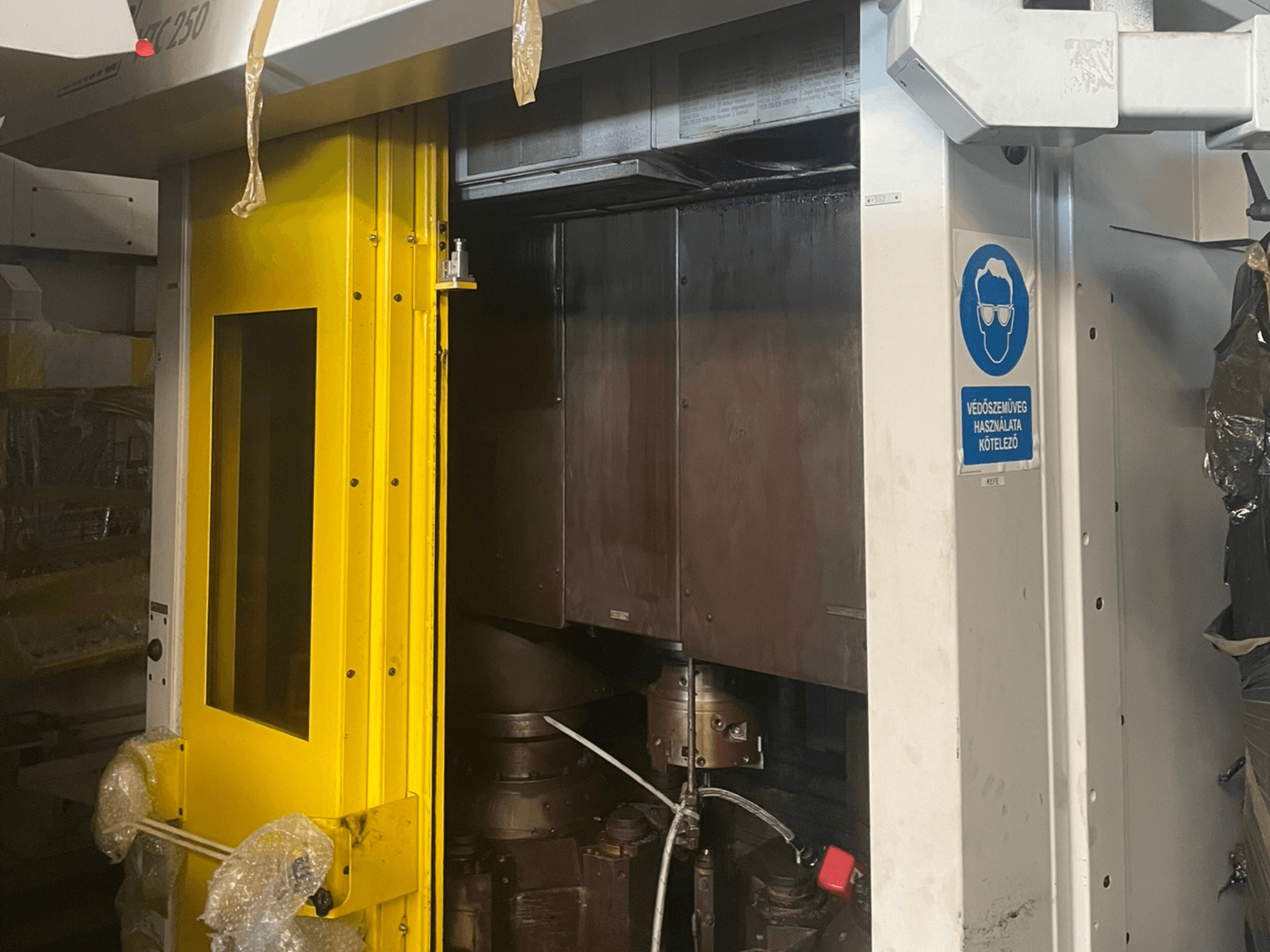 Keltainen koneen sisäänkäyntiovi, jossa on turvamerkki, etukuva teollisuuskoneesta malli Z250, jossa näkyvät koneen sisäiset osat.