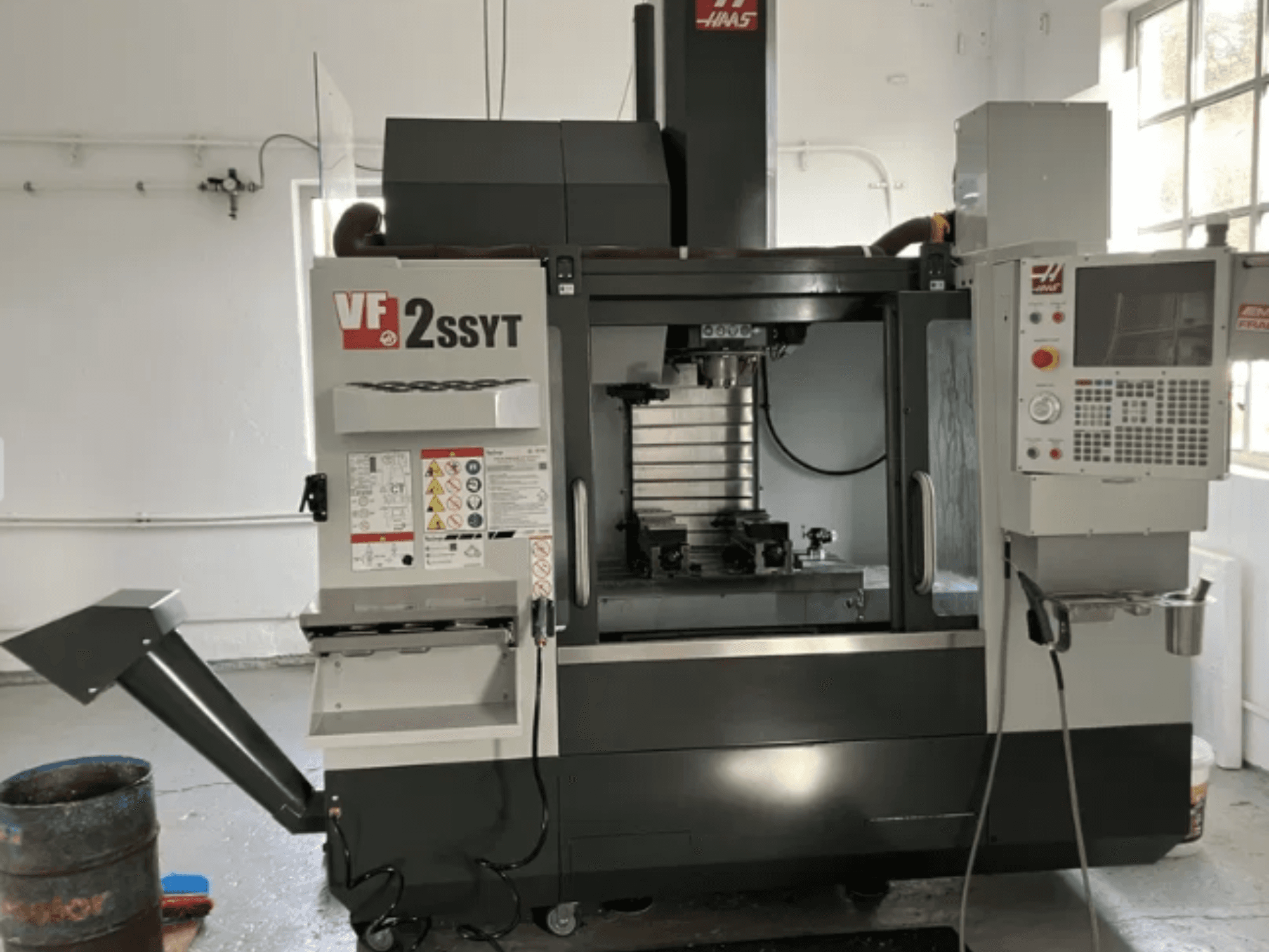 Haas VF-2SSYT CNC-jyrsin, etukuva, jossa on ohjauspaneeli, työkalunpidin ja jäähdytysjärjestelmä metallin työstöön.
