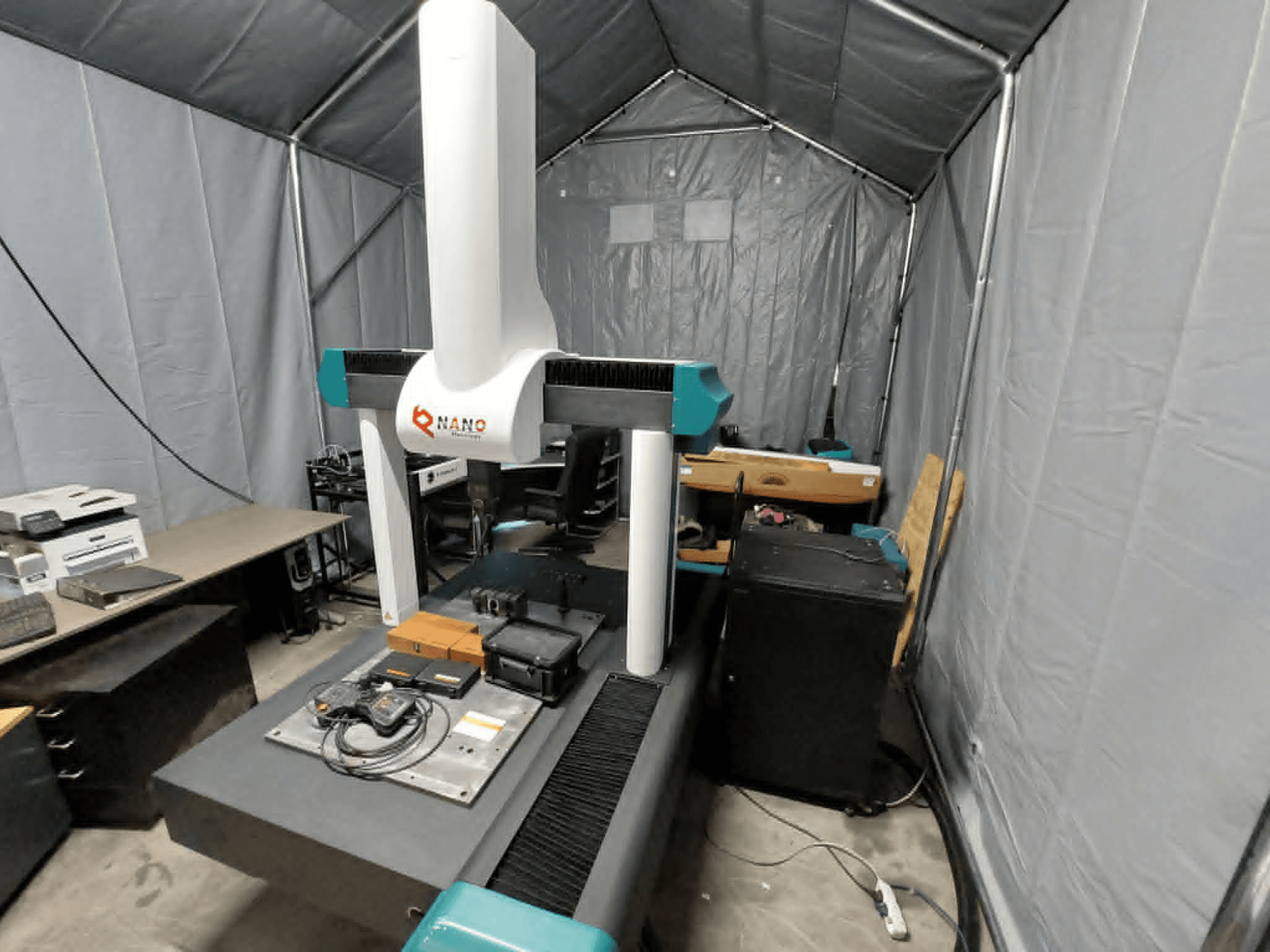 NANO METROLOGY Micr 7106 CMM teltassa; etukuva, jossa näkyy koneen varsi ja mittausalusta lisävarusteineen.