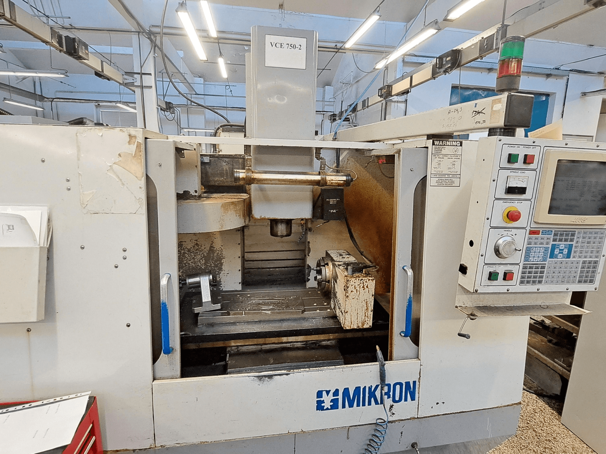 Mikron VCE 750-2 CNC-jyrsinkone, etukuva, jossa ohjauspaneeli ja kara työstöalueella, näkyy kulumista ja likaa.