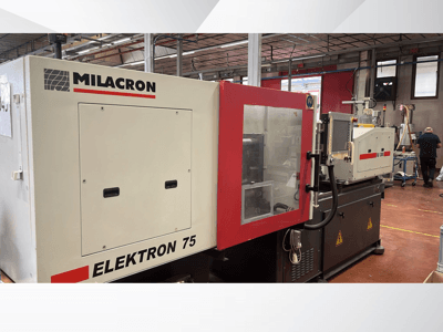 Milacron Elektron 75 -ruiskuvalukone työpajassa, sivukuva, jossa näkyy sen ohjauspaneeli ja mekaaniset osat.