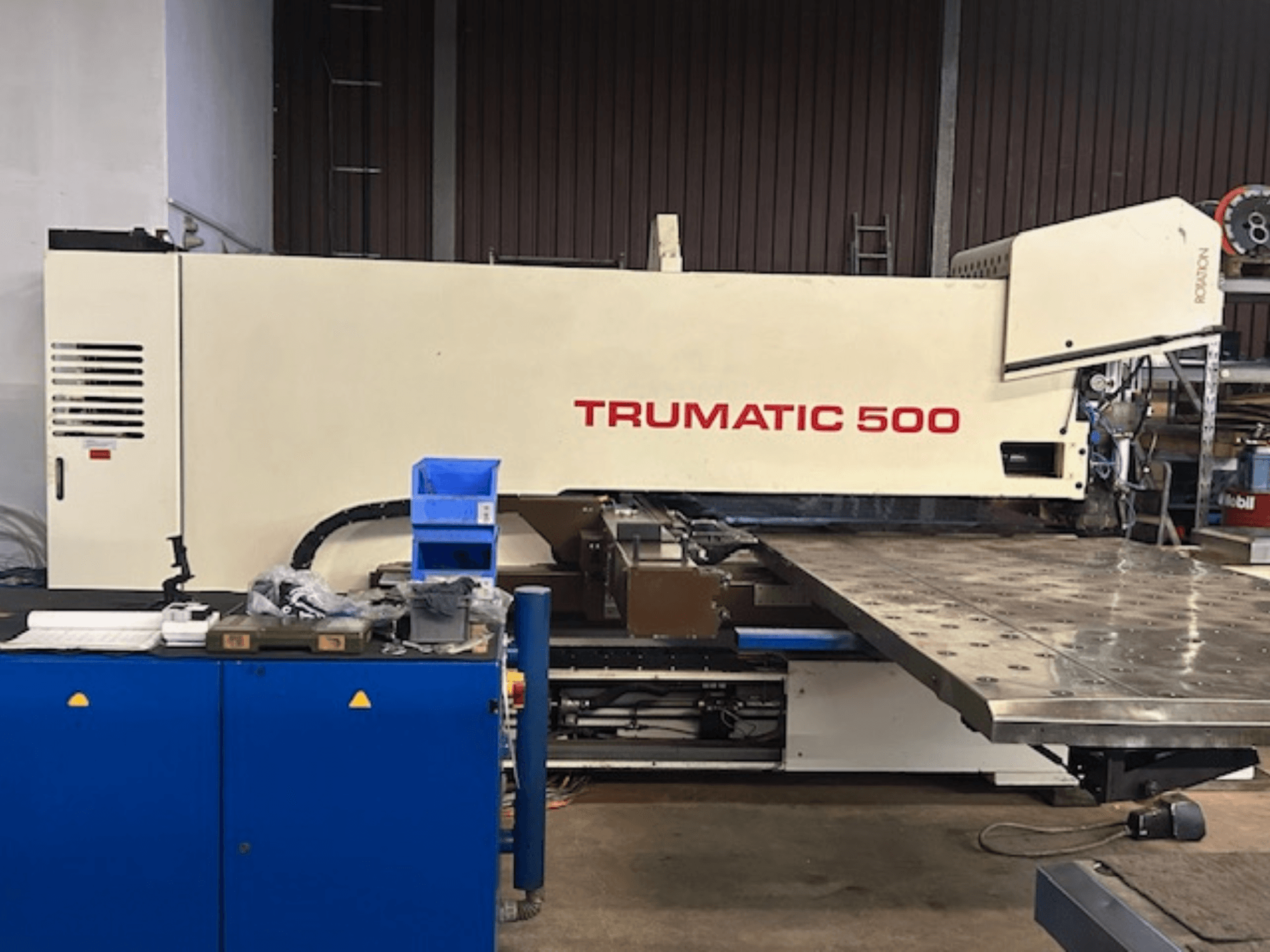TRUMPF TRUMATIC 500 CNC-lyöntikone, etukuva, jossa on ohjauspaneeli ja suuri työpöytä, jossa on rei'itetty pinta.