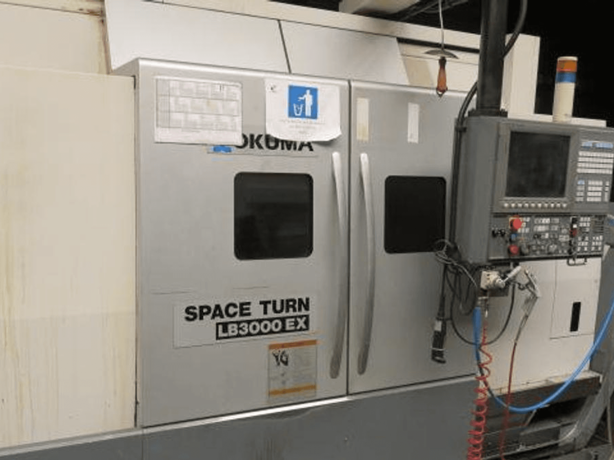Okuma Space Turn LB3000 EX CNC-sorvi, sivukuva, jossa on ohjauspaneeli, kaksi ovea ja näkyvät johdotukset.