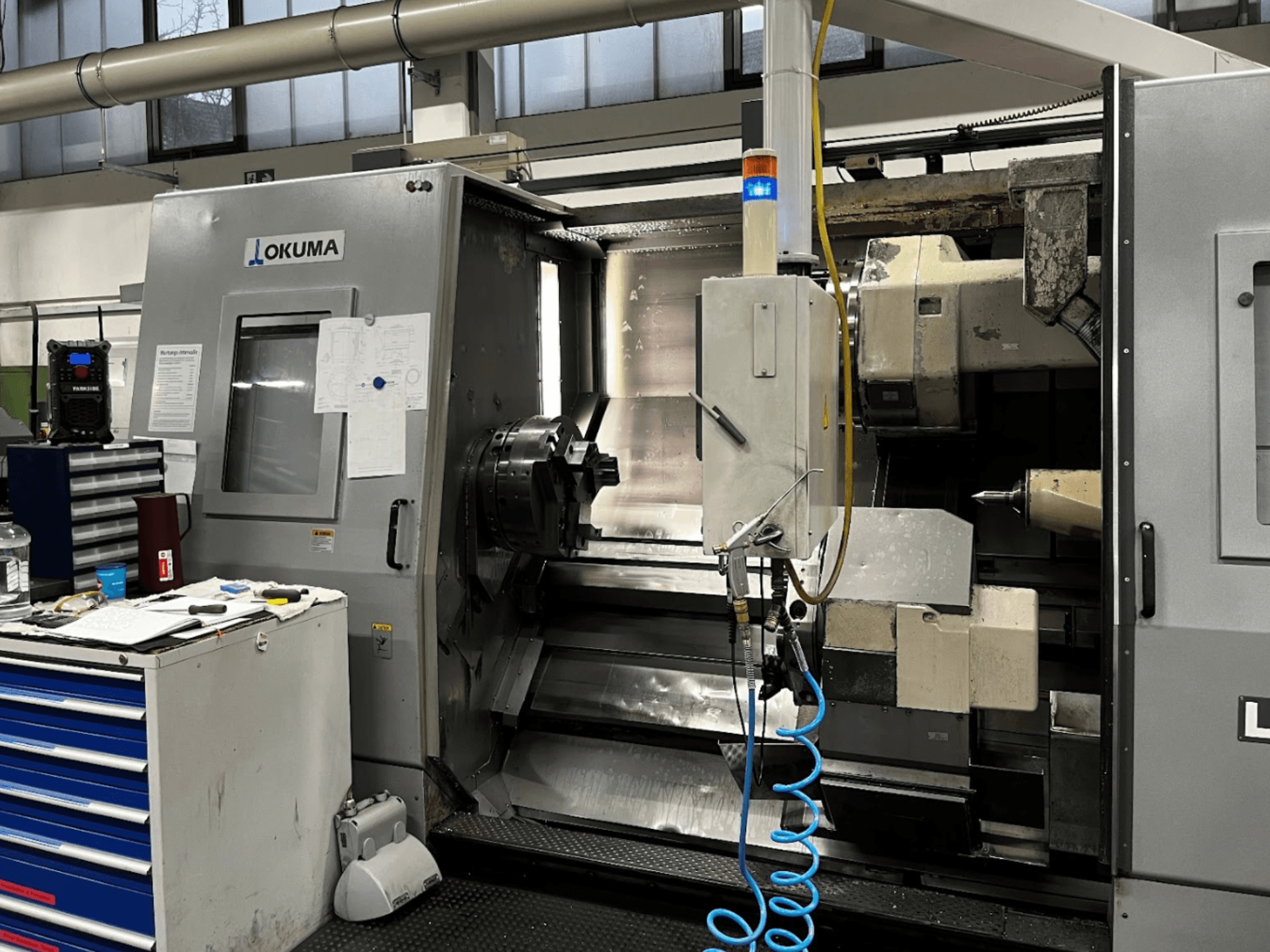 Okuma LU35-M vaakasuora sorvauskone, etukuva. Ohjauspaneeli, työkalut ja suuri työstöruuvi koneistustoimintoja varten.