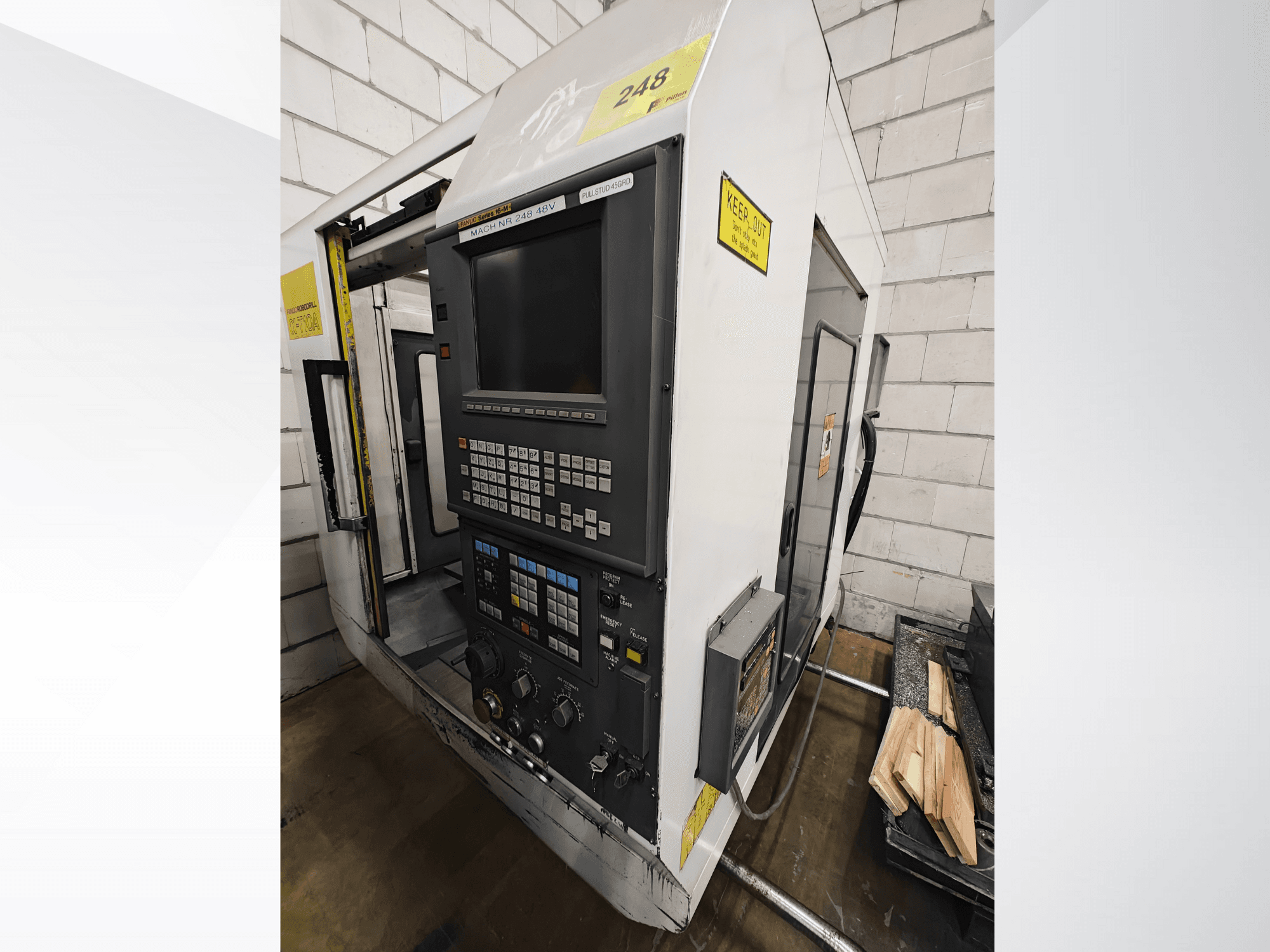 CNC-koneen malli nro 248, etukuva, jossa on ohjauspaneeli, jossa on painikkeet ja näyttö, sekä puukappaleita hyllyllä lähellä.